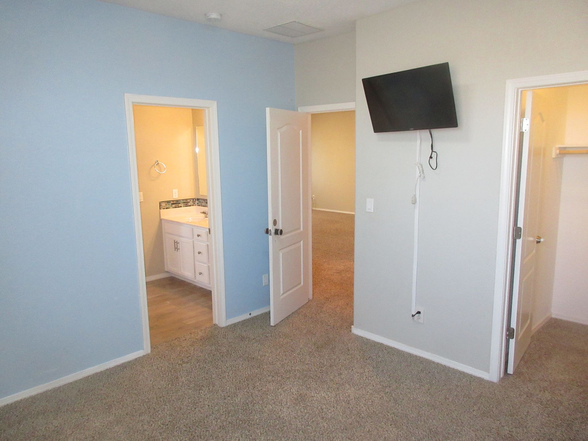 A bedroom with blue walls and a flat screen tv on the wall.