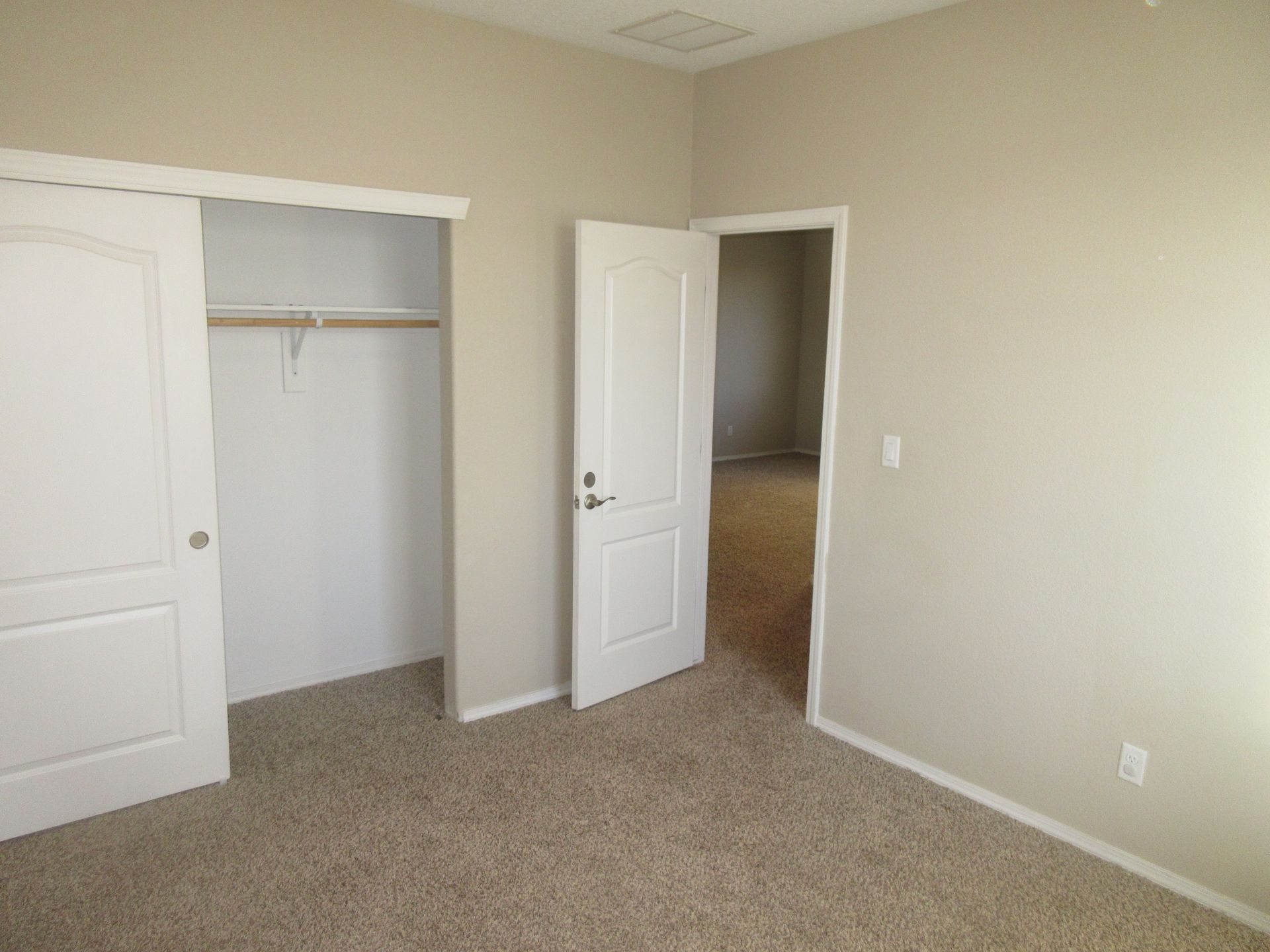 An empty bedroom with a closet and two doors.
