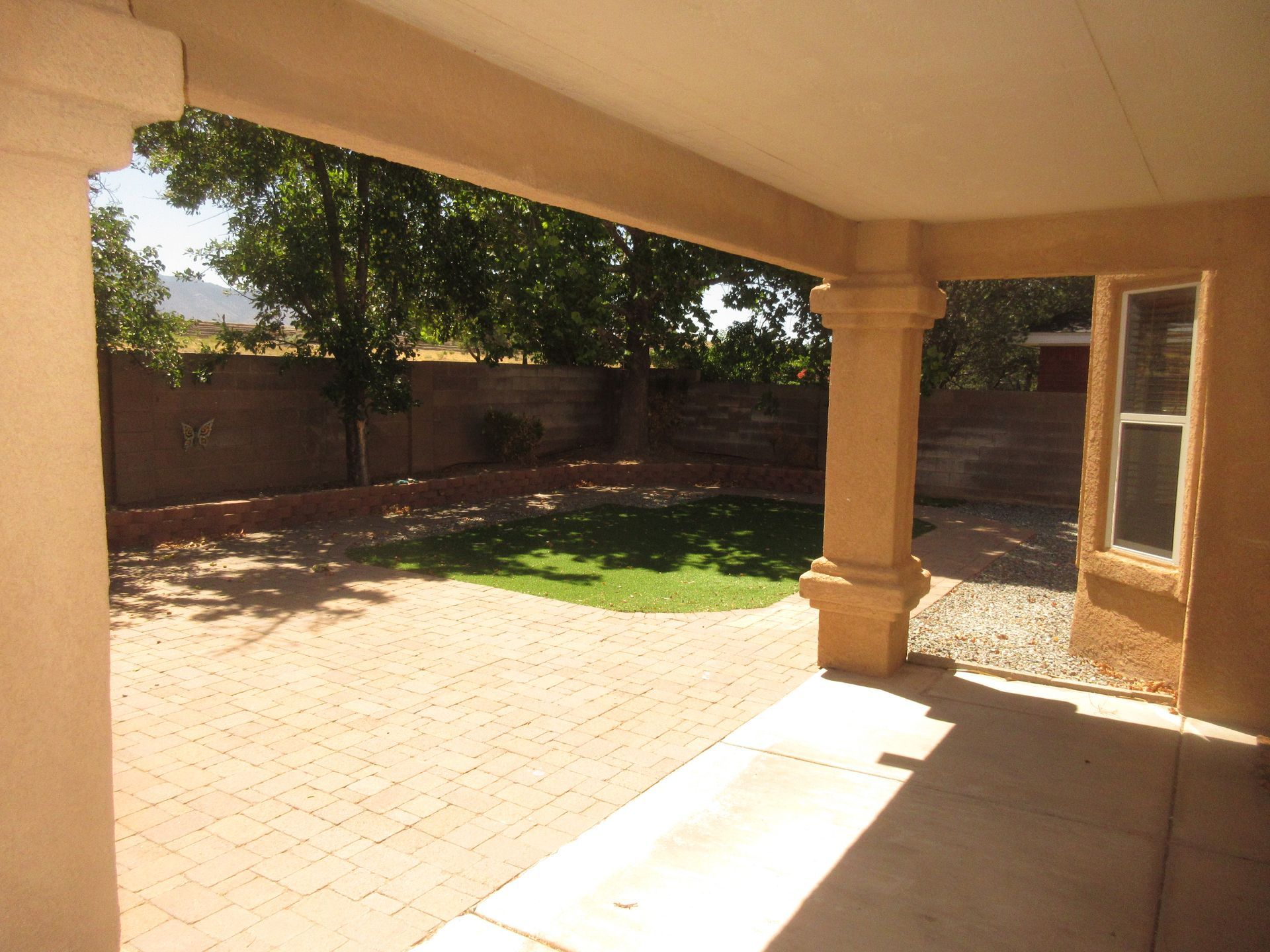 A patio with a window and trees in the background