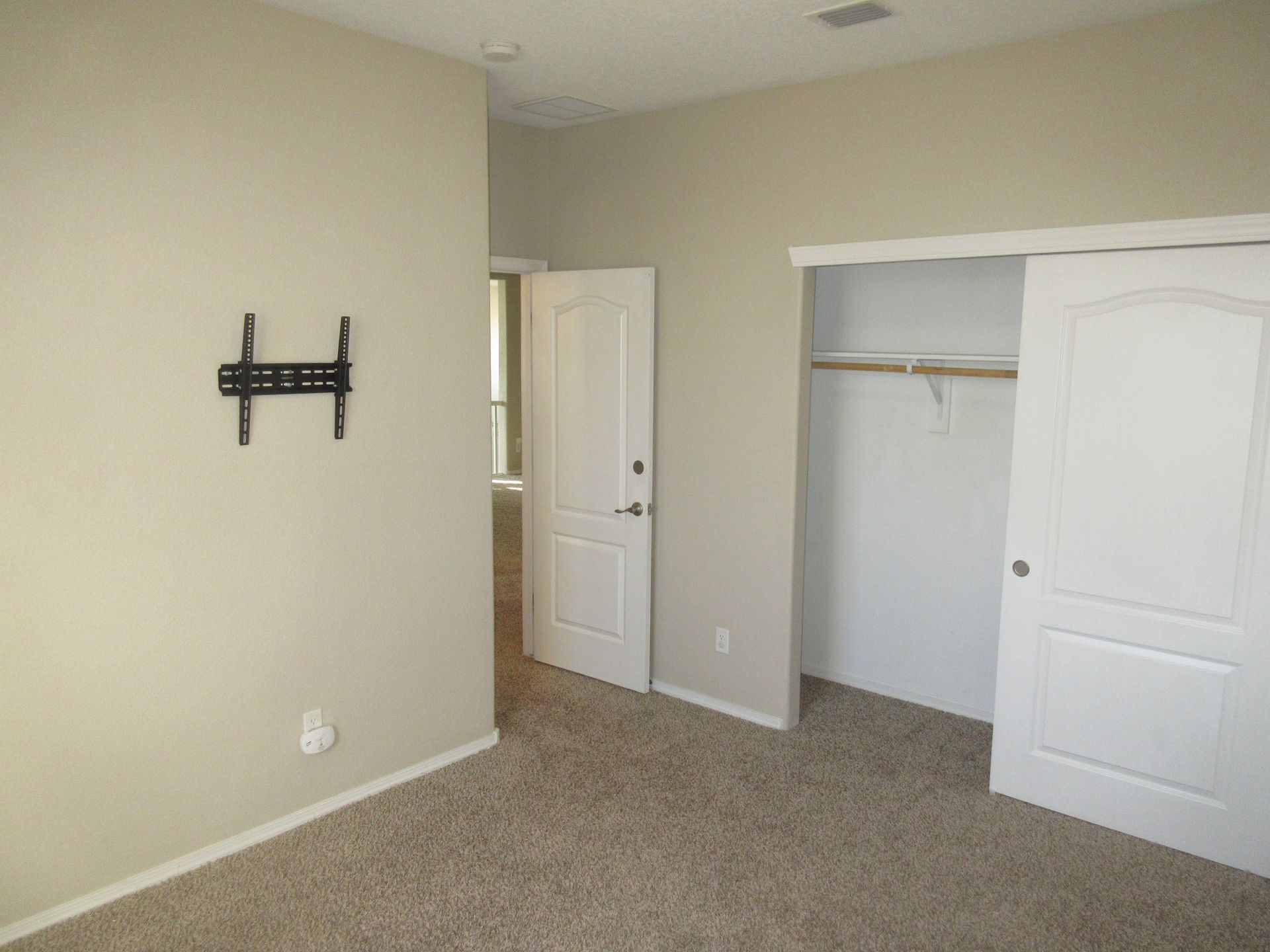 An empty bedroom with a flat screen tv mounted on the wall.