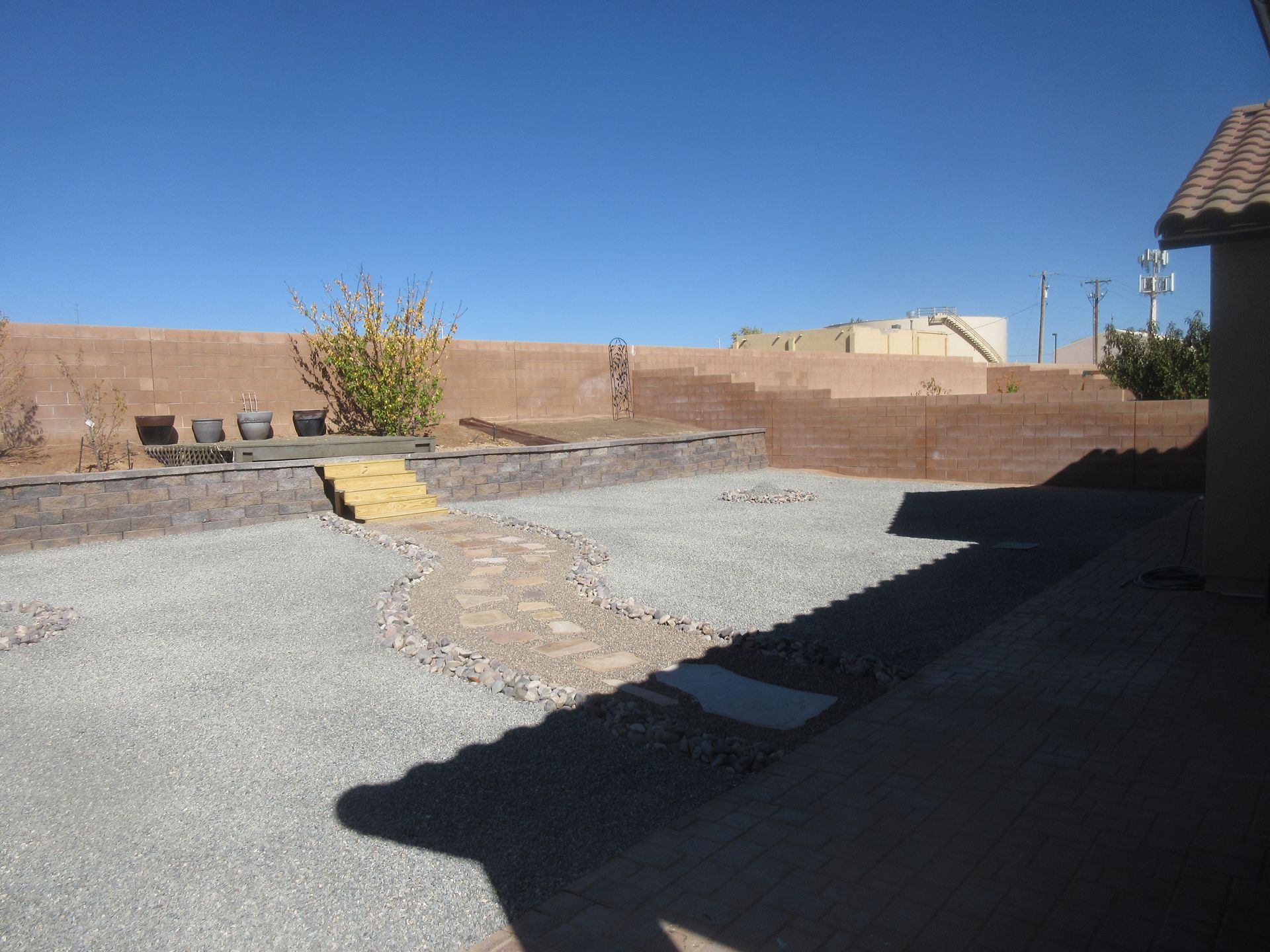 A backyard with gravel and a building in the background