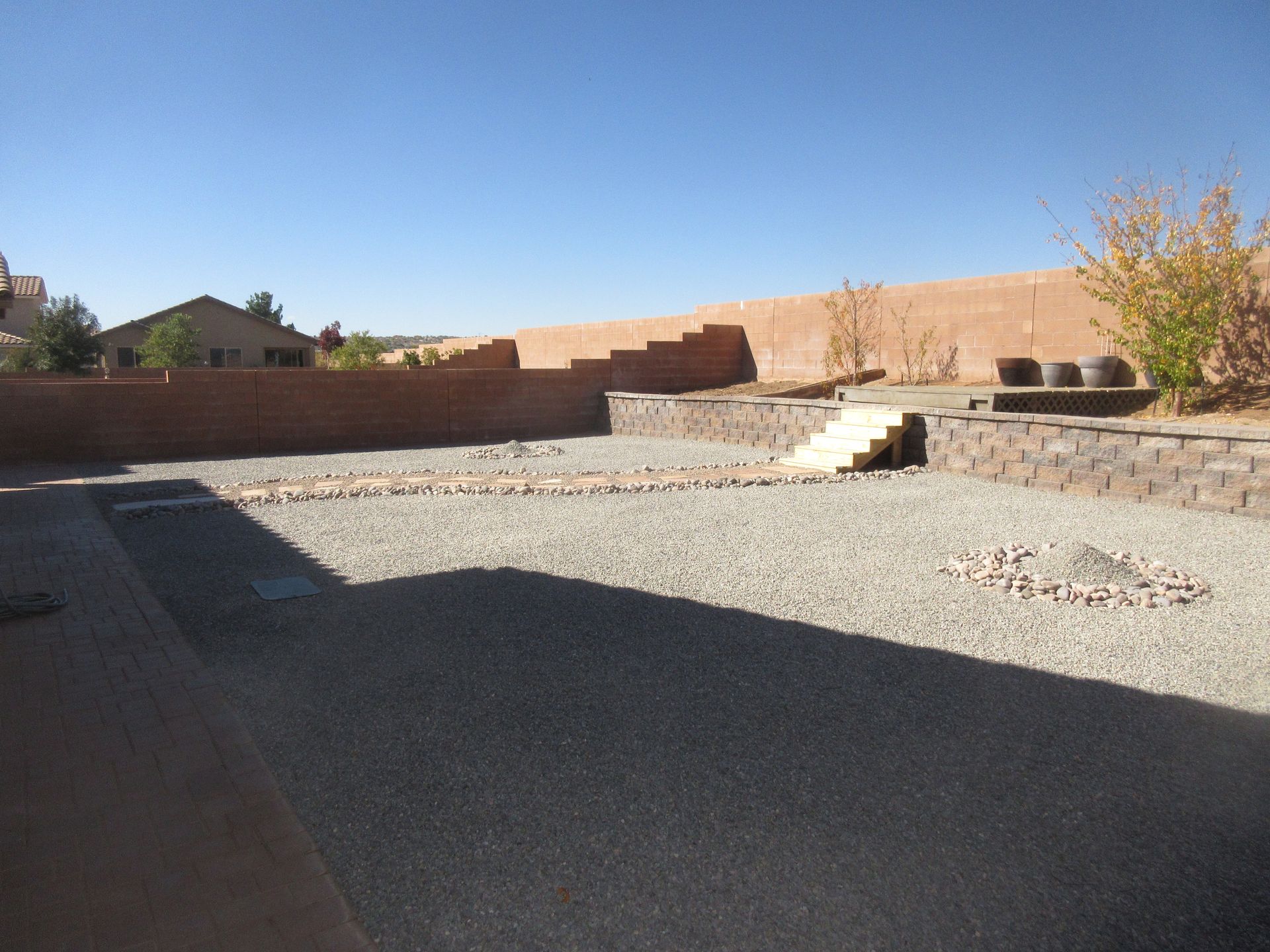 A backyard with gravel and a brick wall