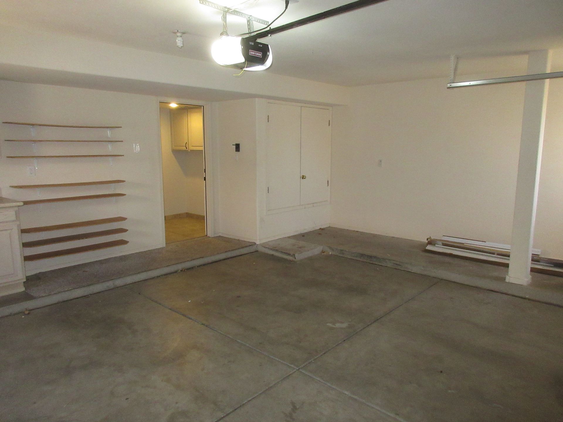 An empty garage with shelves and a garage door open