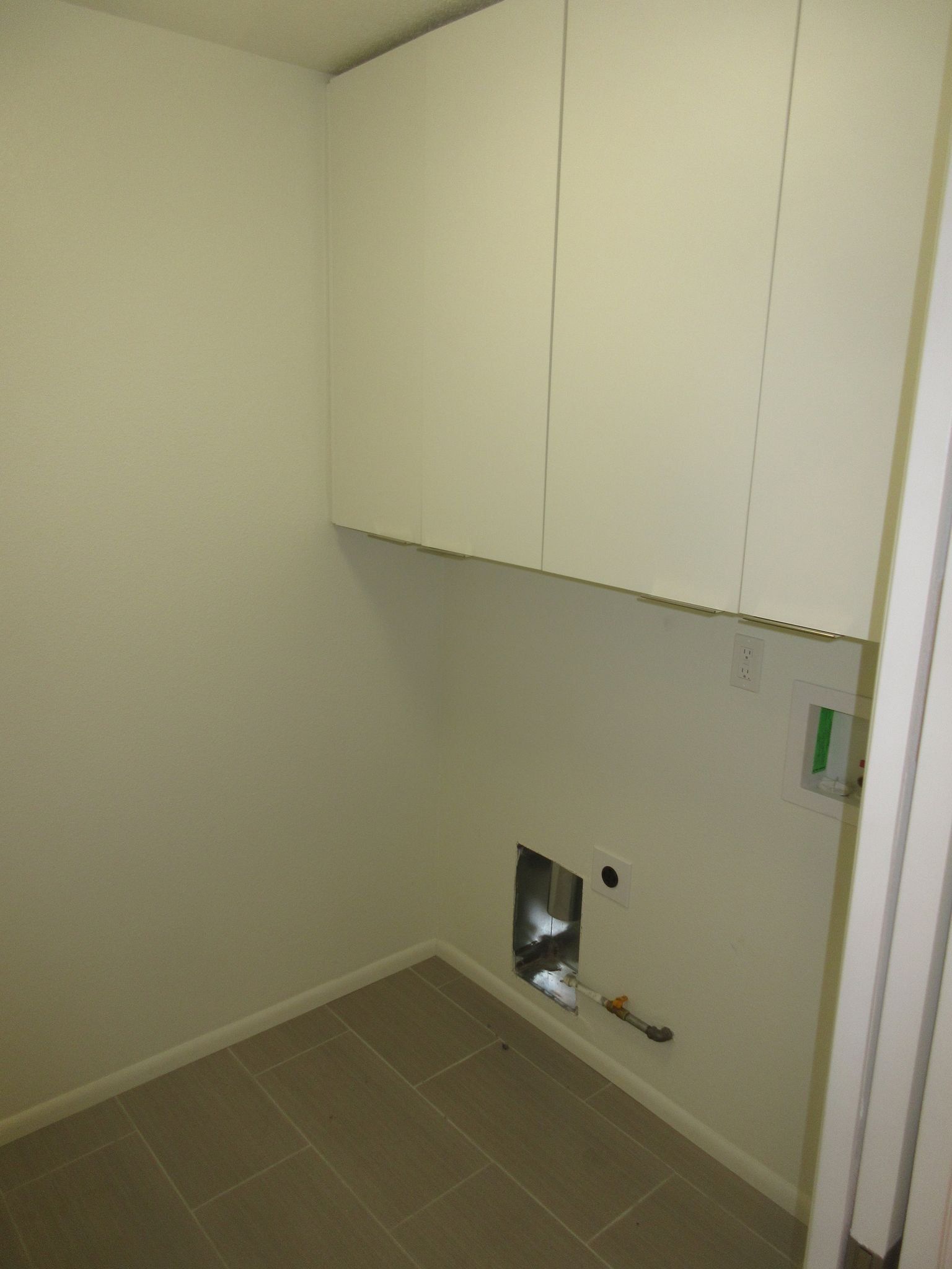 A room with white cabinets and a hole in the wall