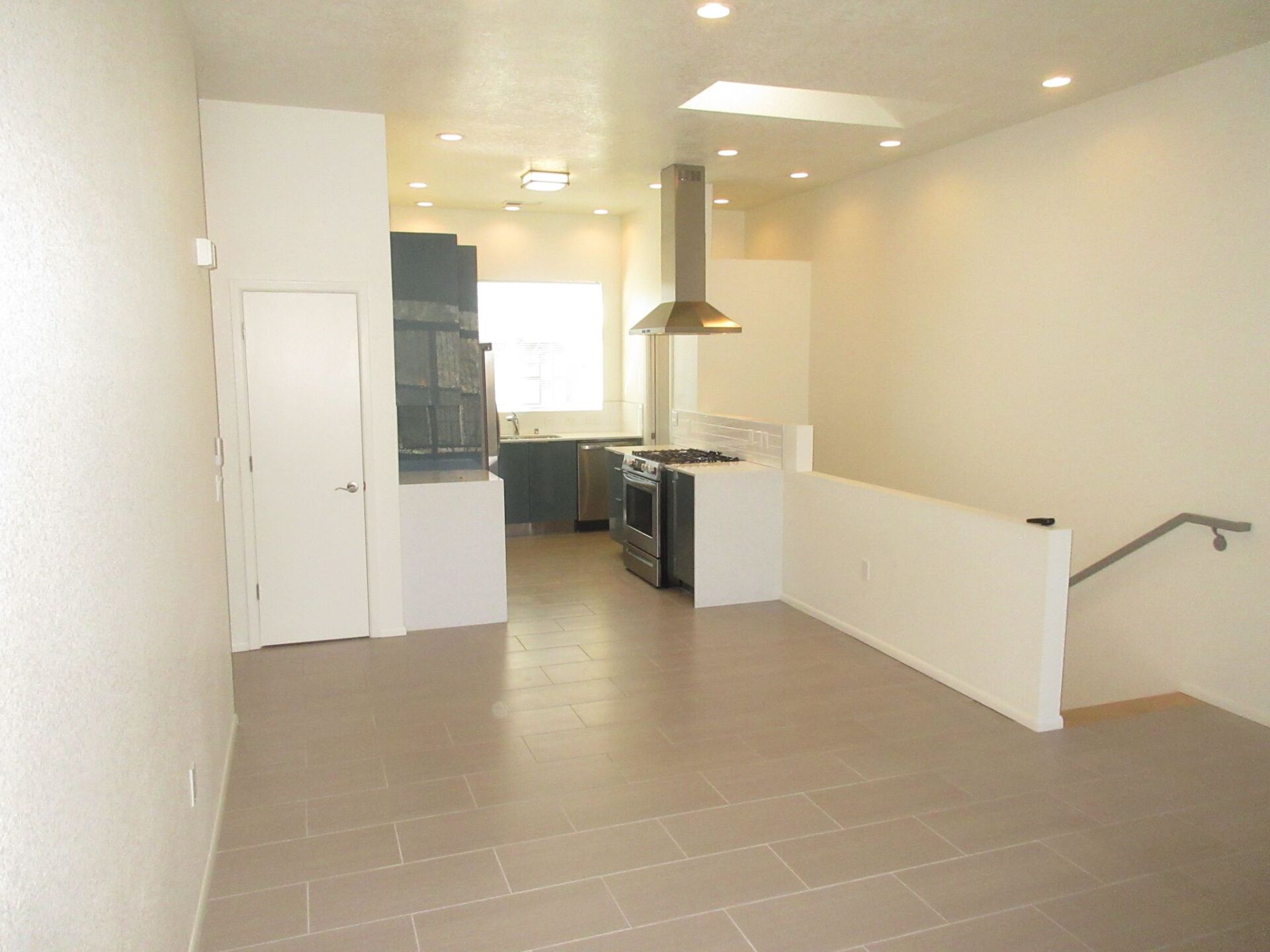 An empty room with a staircase leading to a kitchen