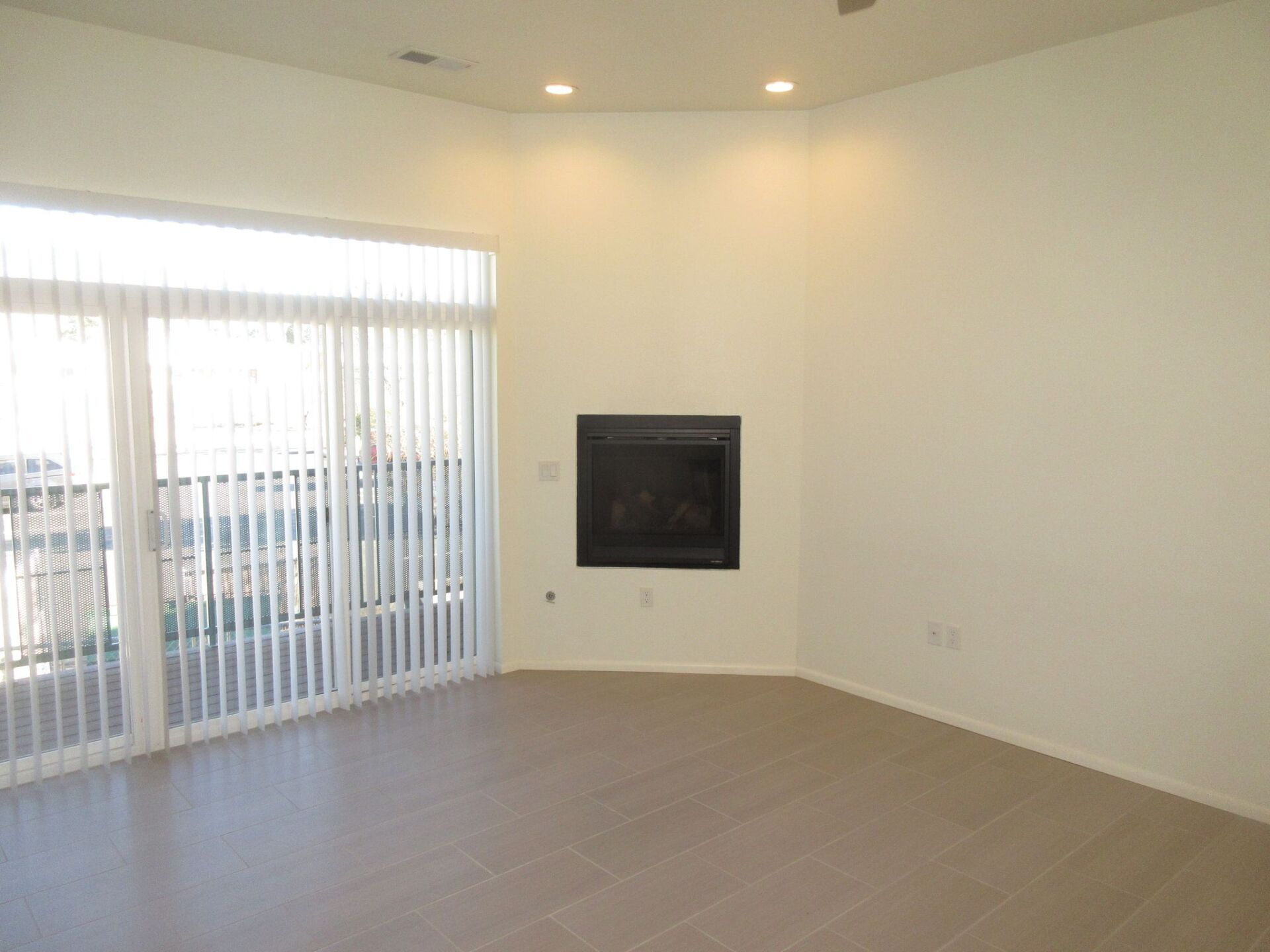 An empty living room with a fireplace and sliding glass doors.