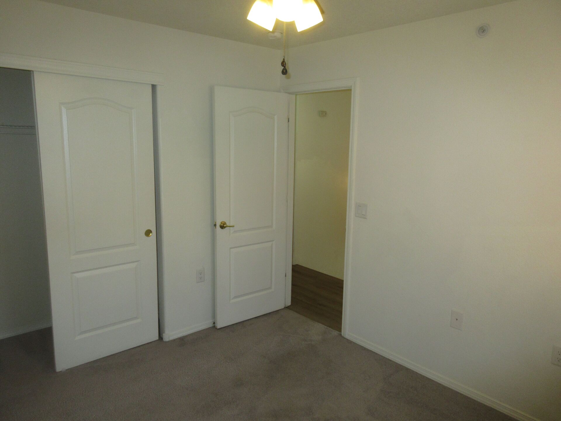 An empty bedroom with two white doors and a ceiling fan.