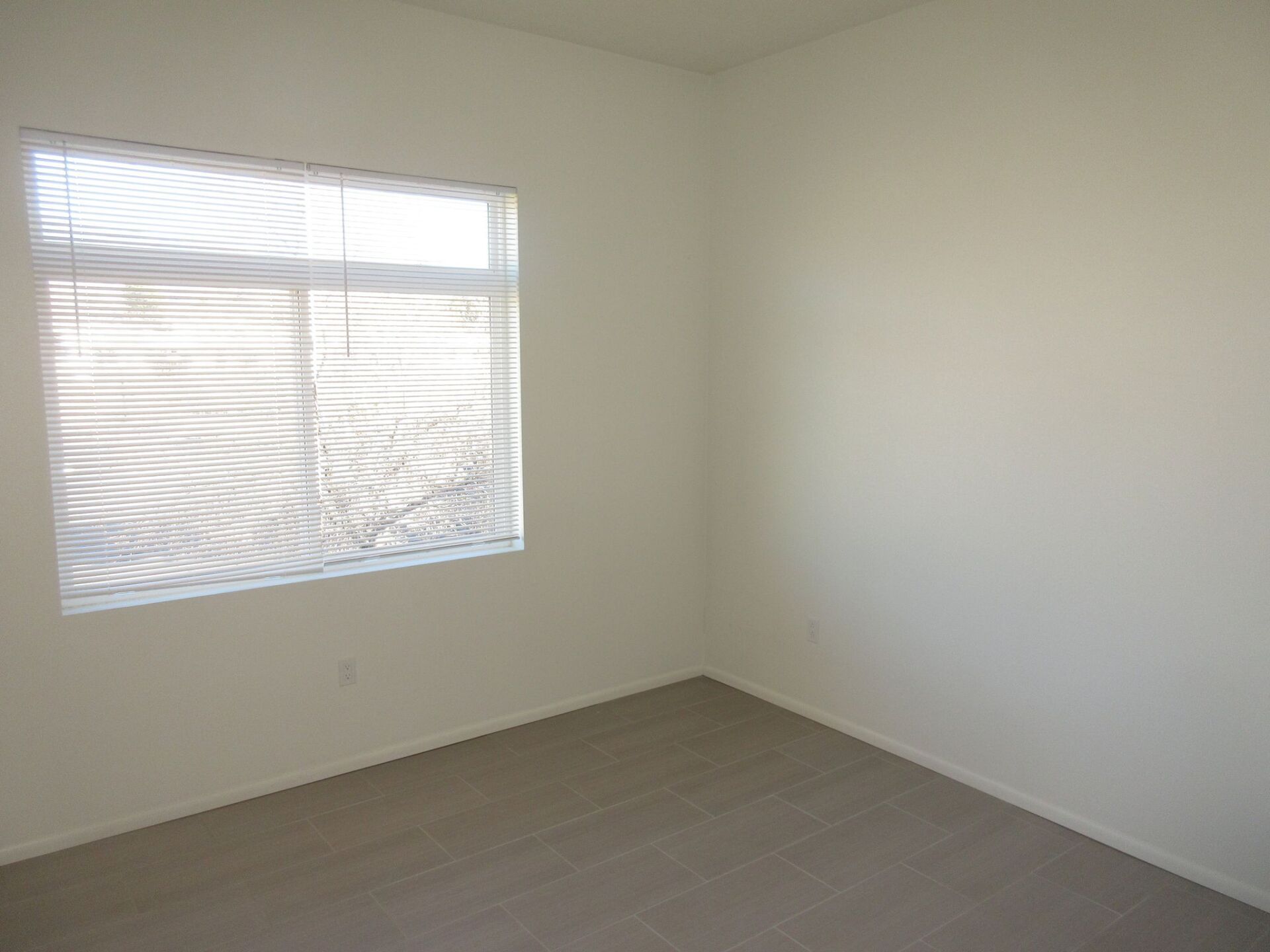 An empty room with a window and blinds on it.