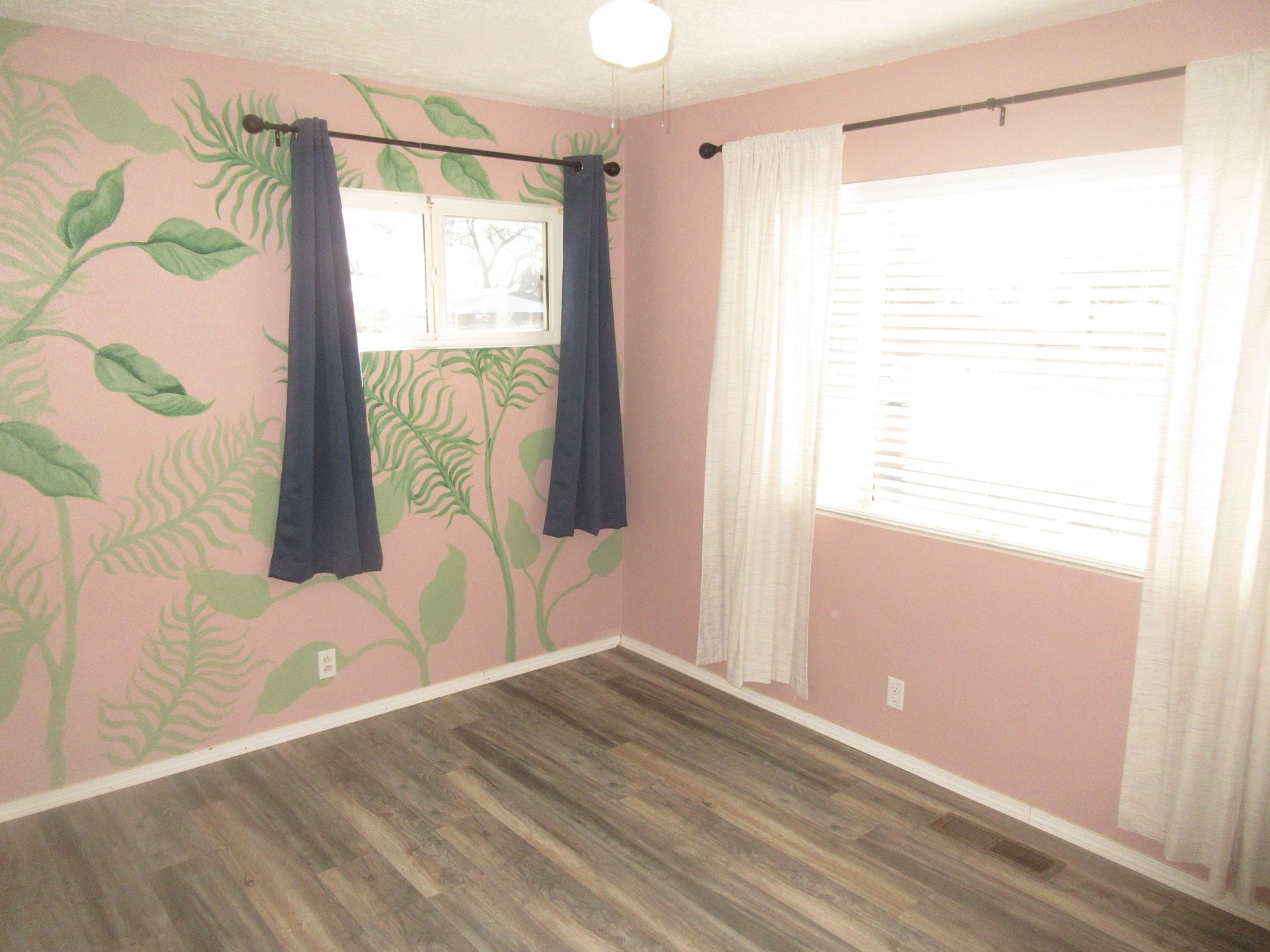 A room with a painting on the wall and a window.