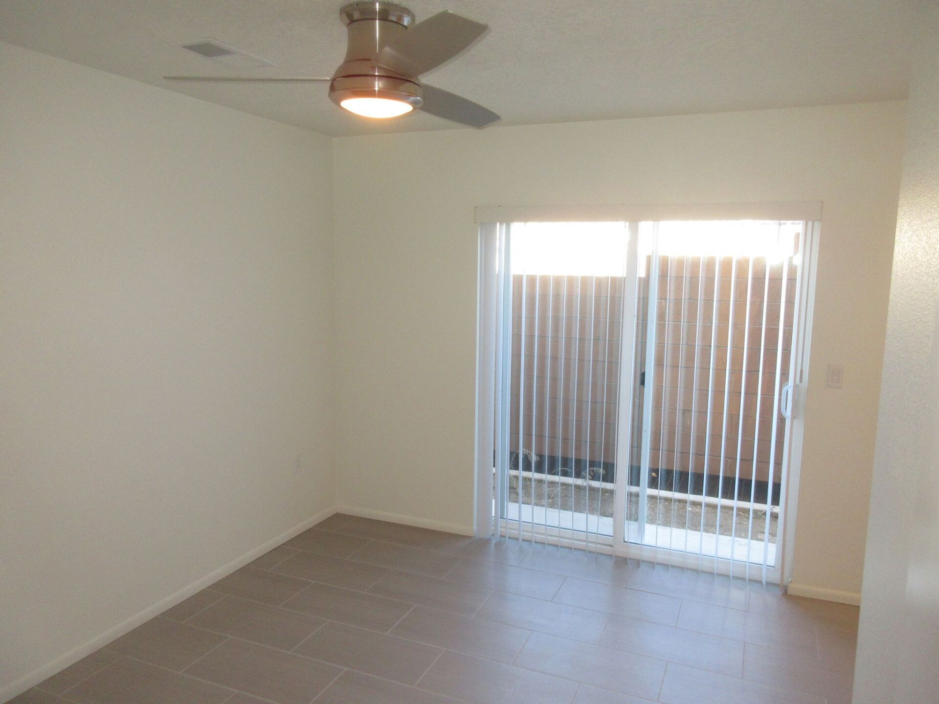 An empty room with a ceiling fan and sliding glass doors