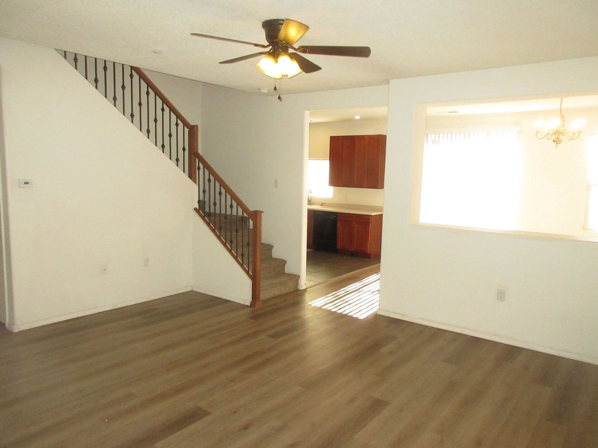 An empty living room with hardwood floors and a ceiling fan.