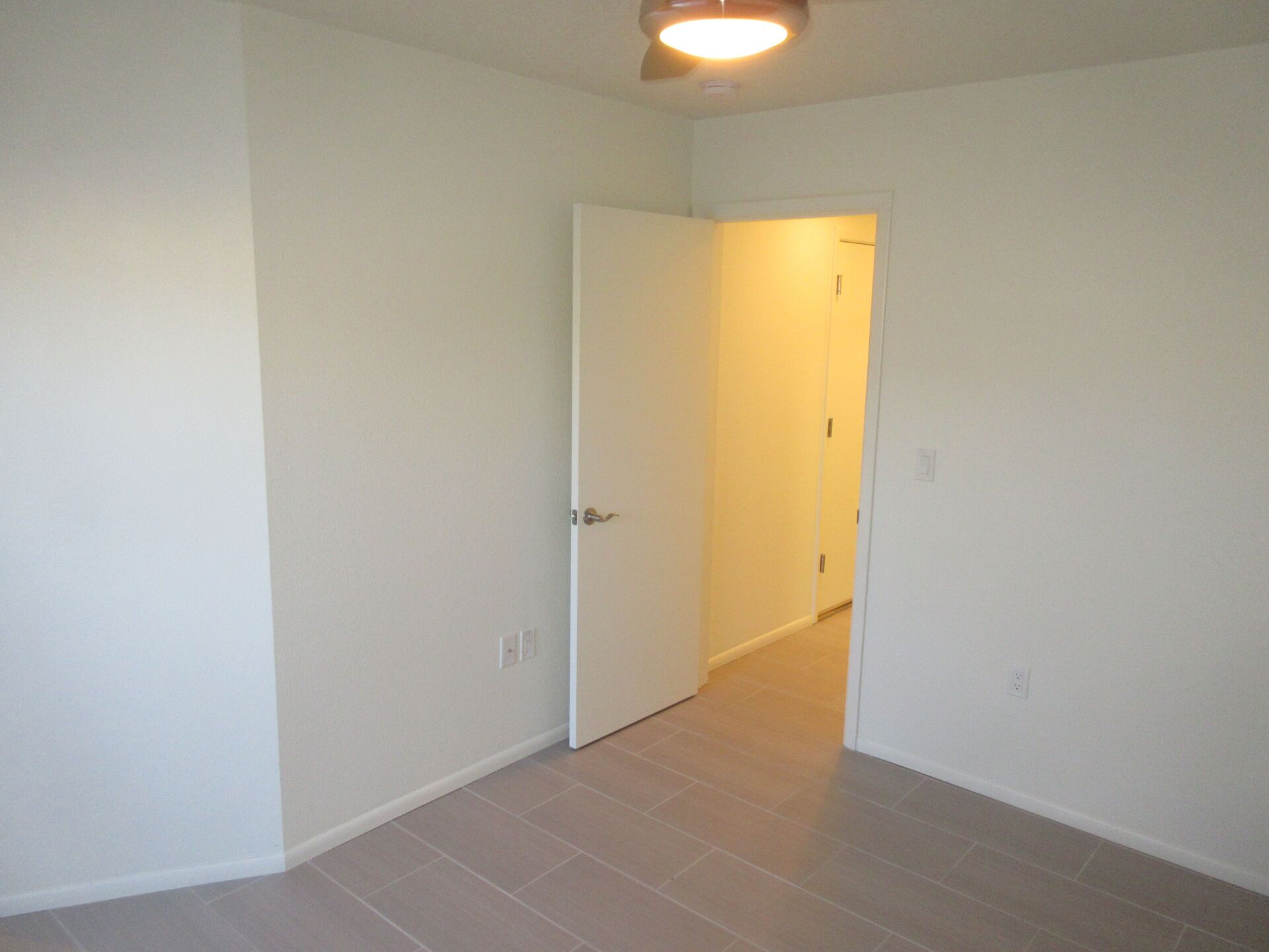 An empty room with a white door and a light on the ceiling