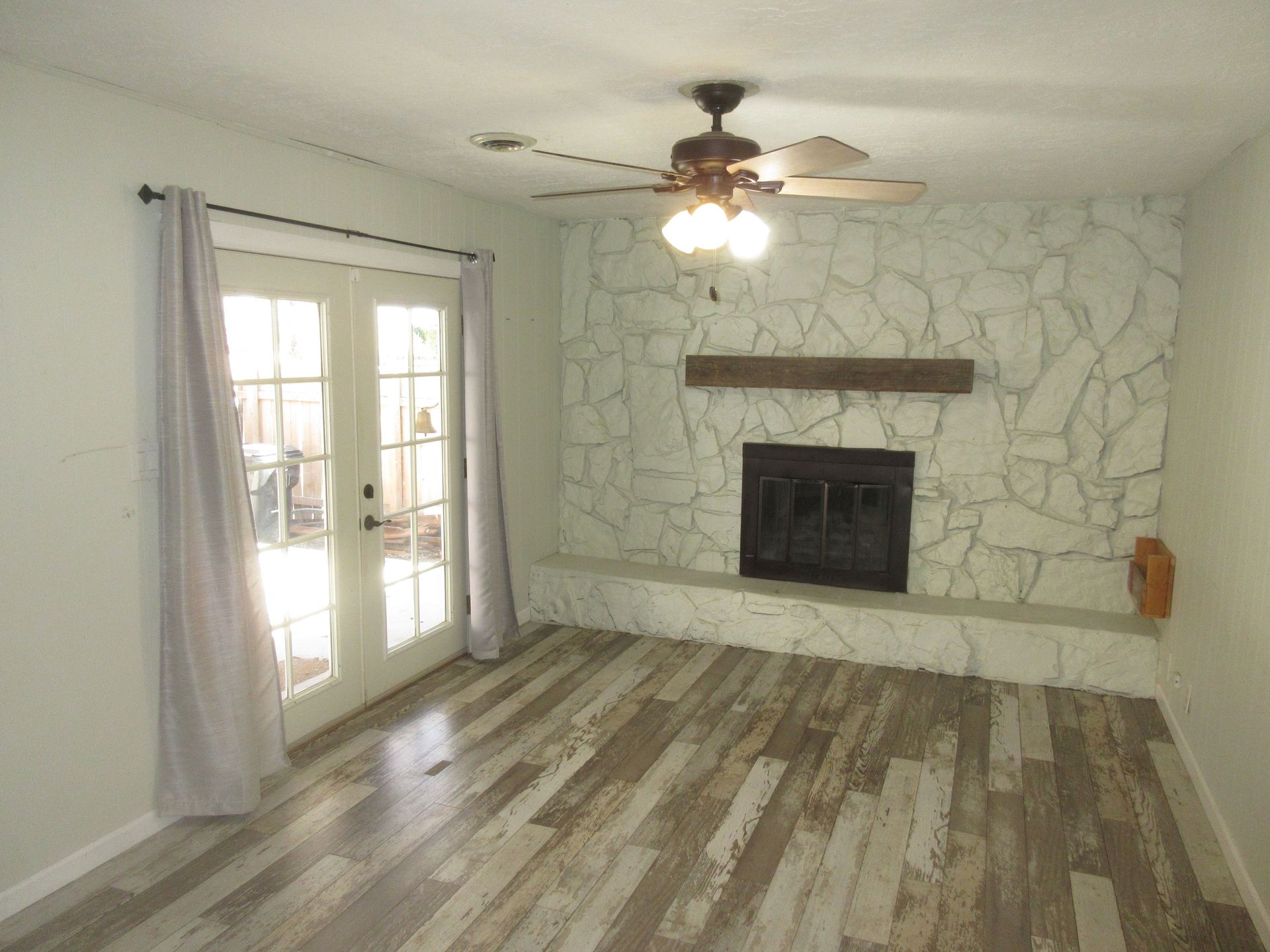 A living room with a fireplace and a ceiling fan.