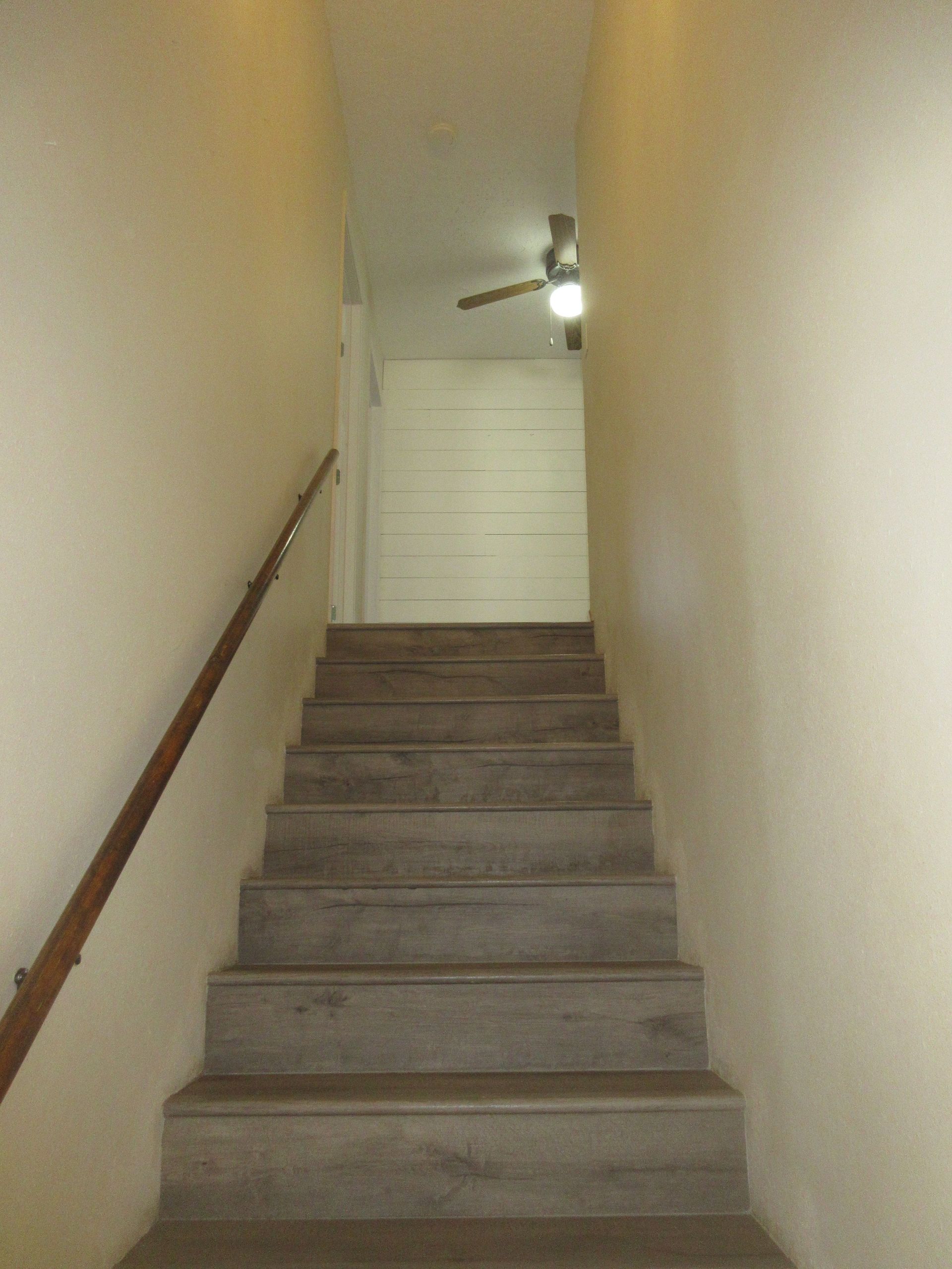 A set of stairs leading up to a room with a ceiling fan.