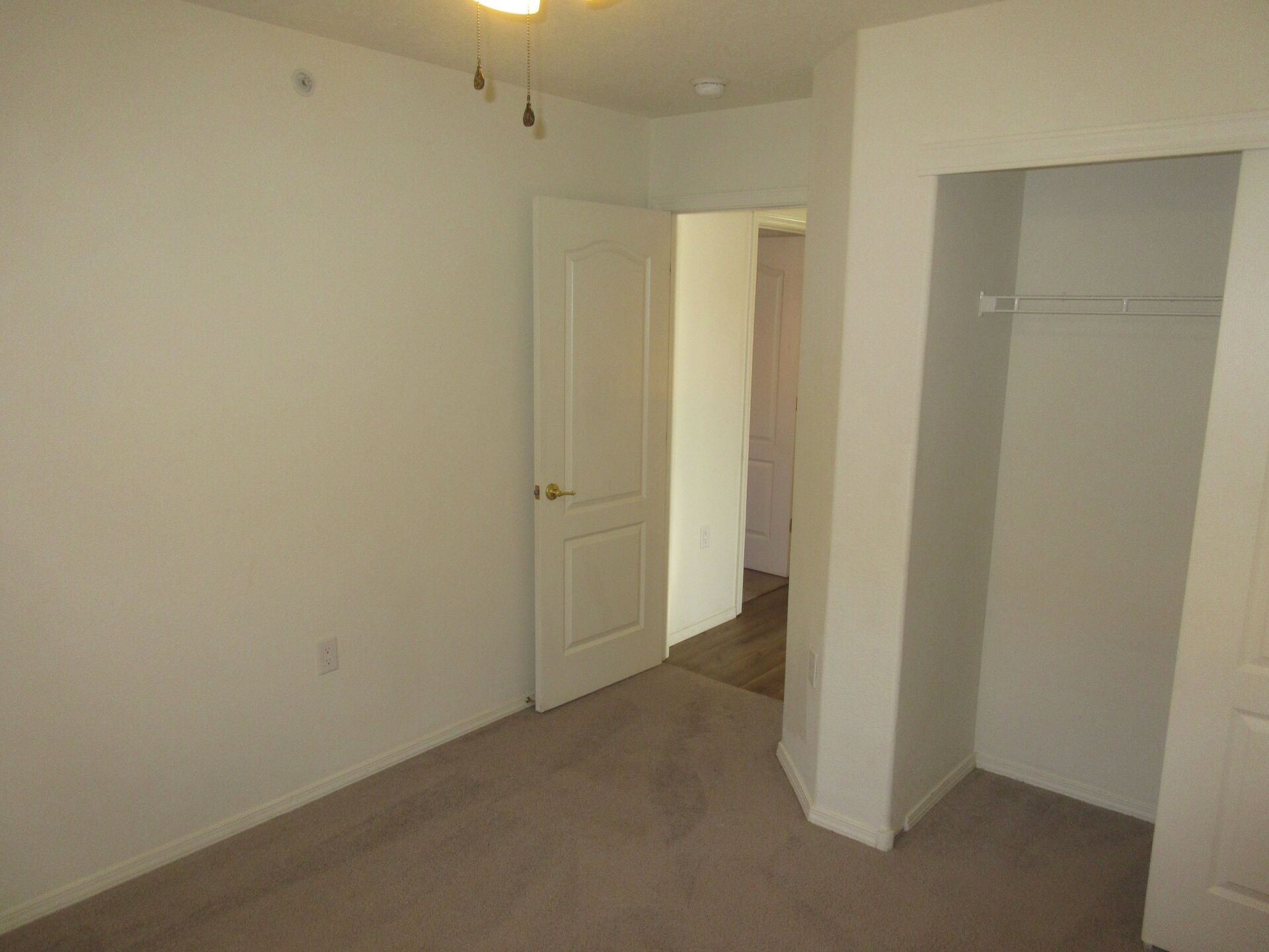 An empty bedroom with a closet and a door.