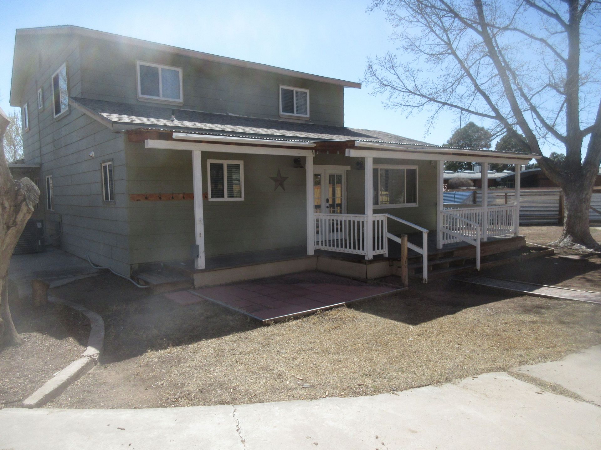 A green house with a white porch and stairs