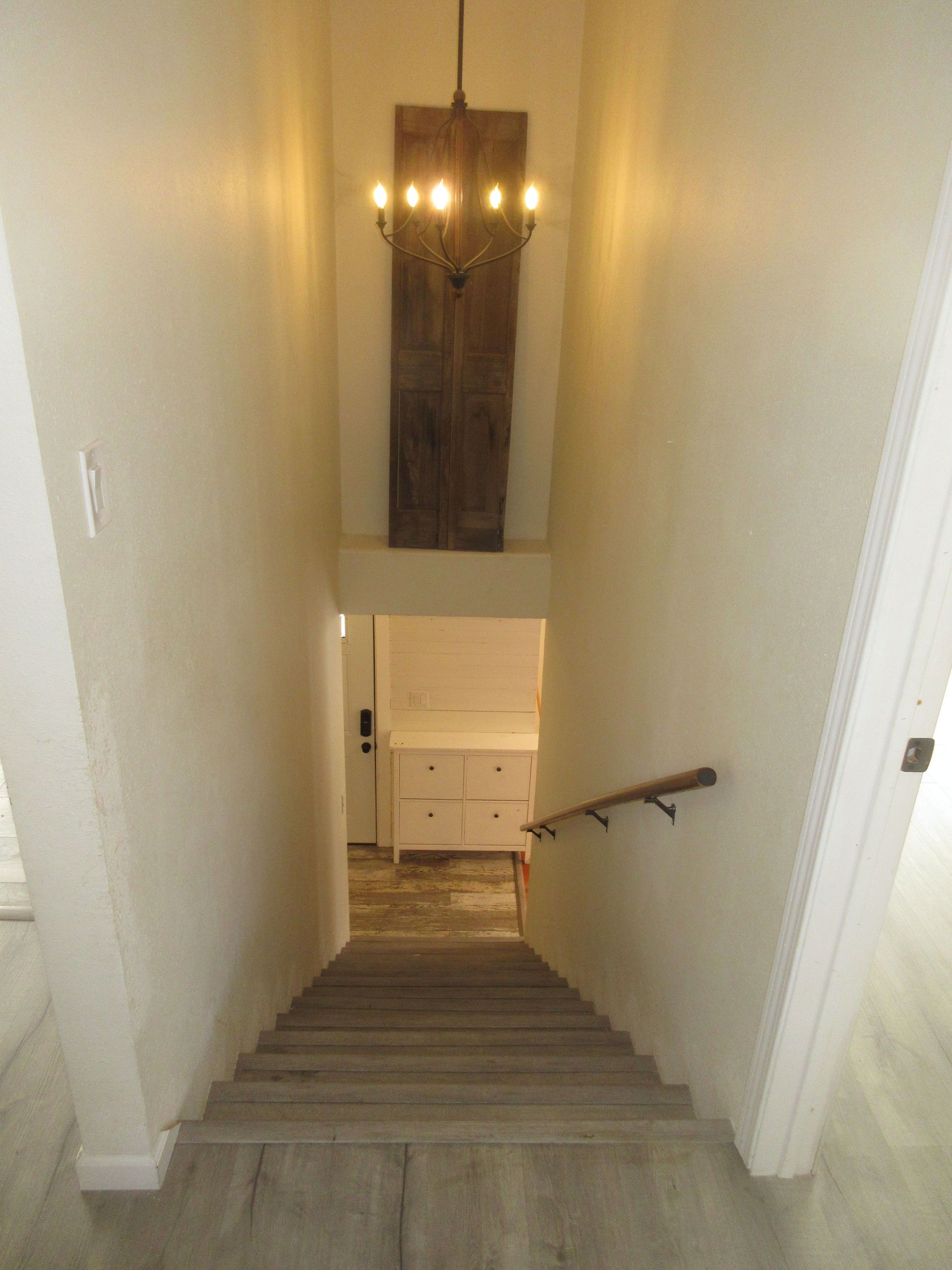 A staircase leading up to the second floor of a house with a chandelier hanging from the ceiling.