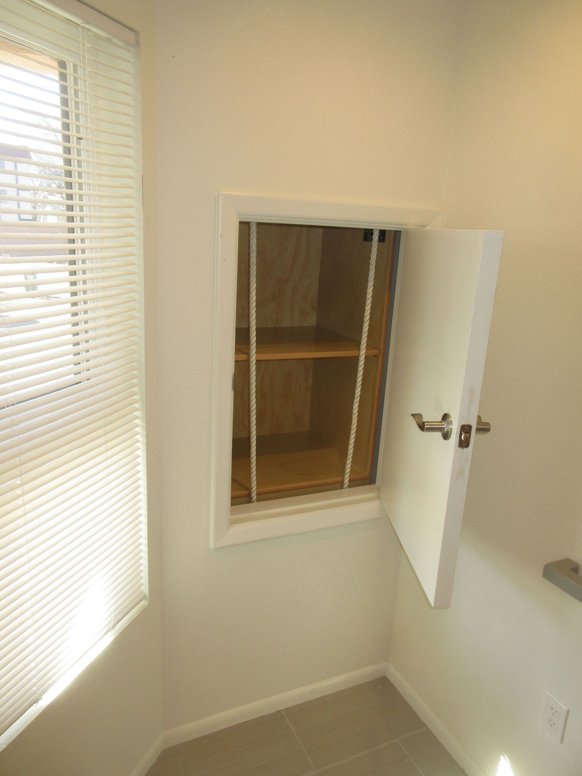 A room with a window and a cabinet with the door open