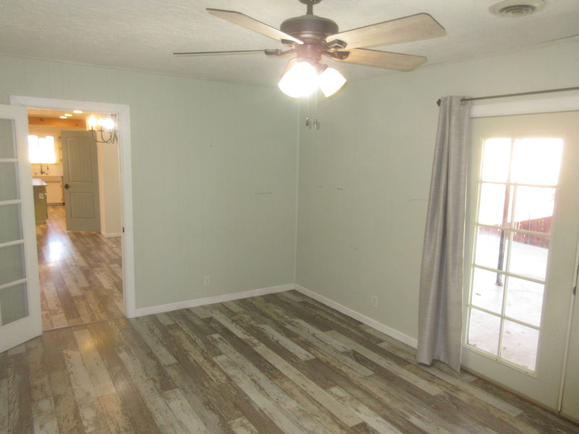 A living room with hardwood floors and a ceiling fan.