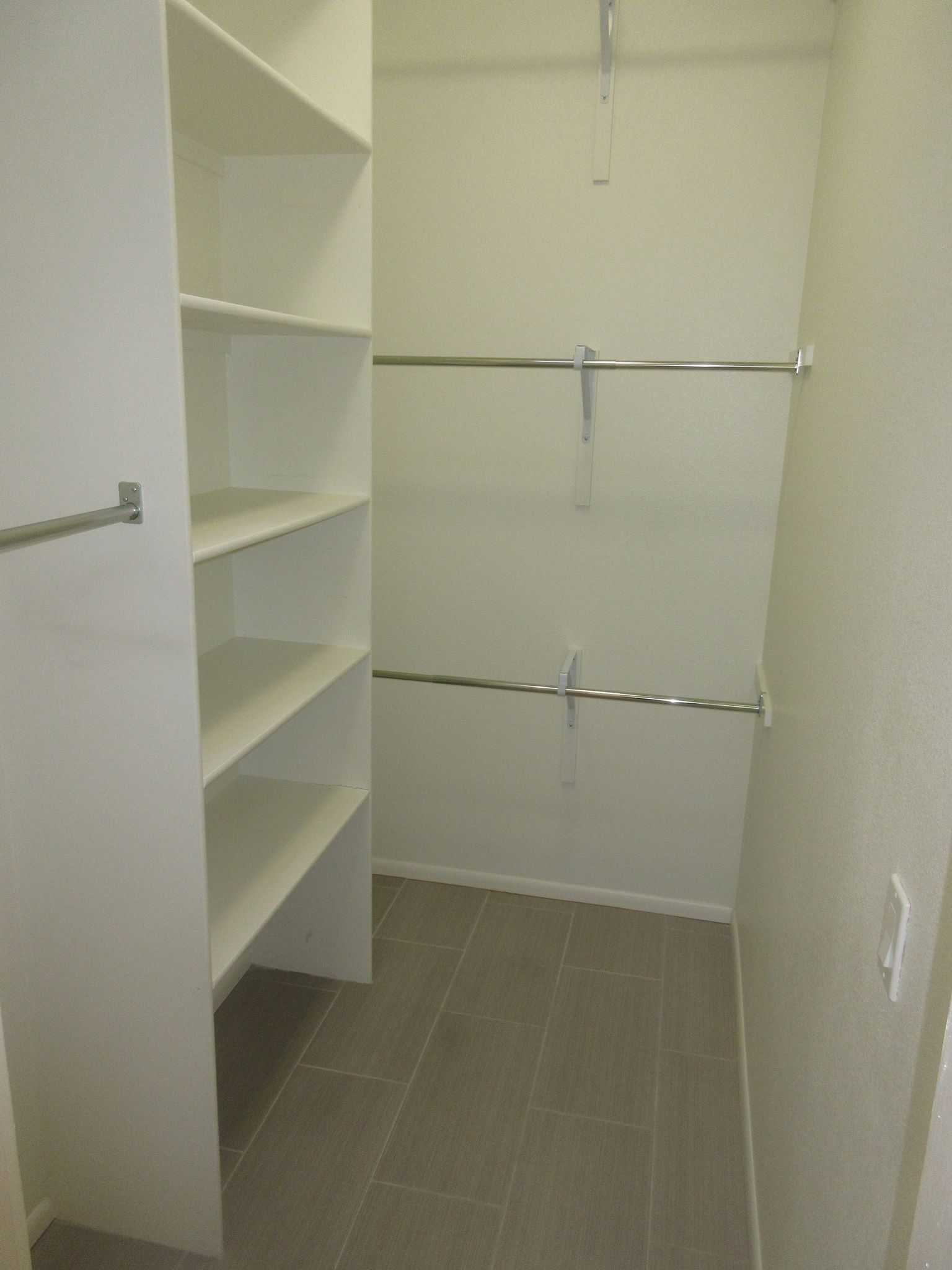 A walk in closet with lots of shelves and clothes racks.