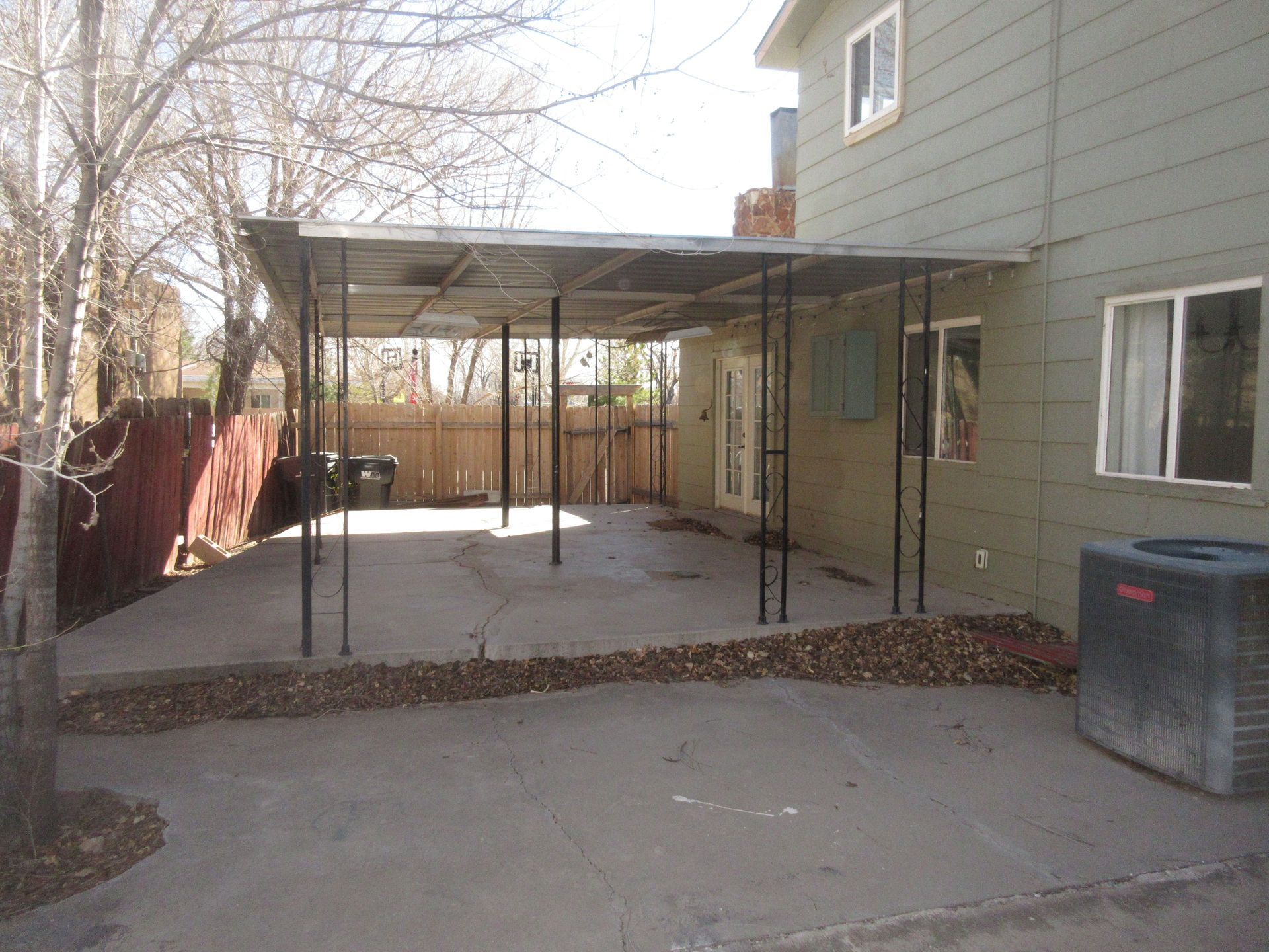 The backyard of a house with a carport and an air conditioner