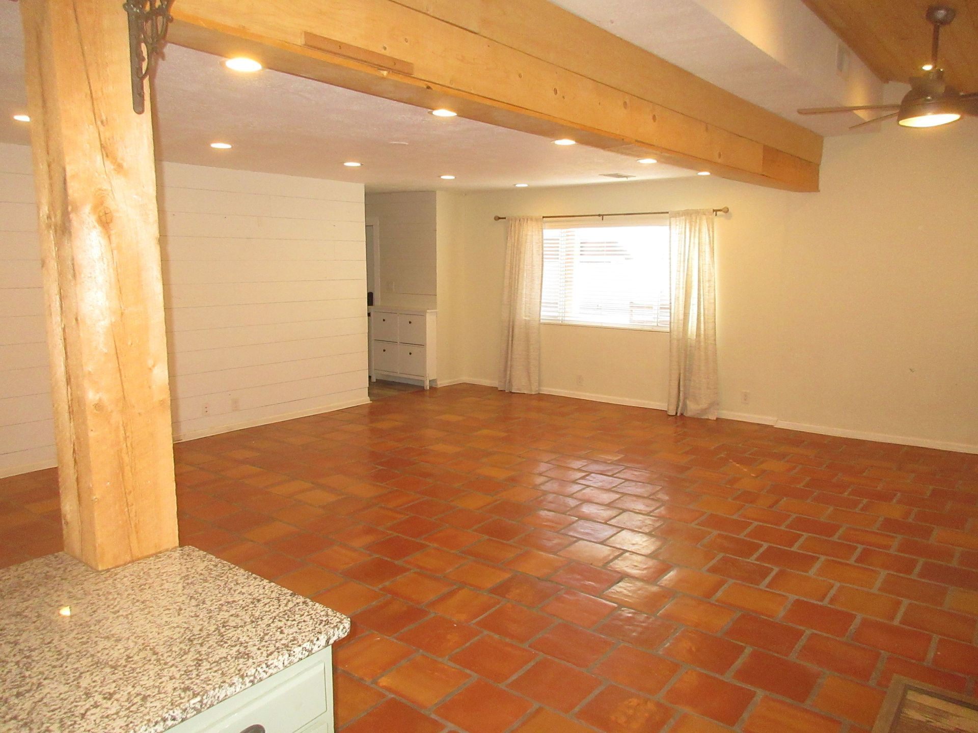 An empty living room with a ceiling fan and a window