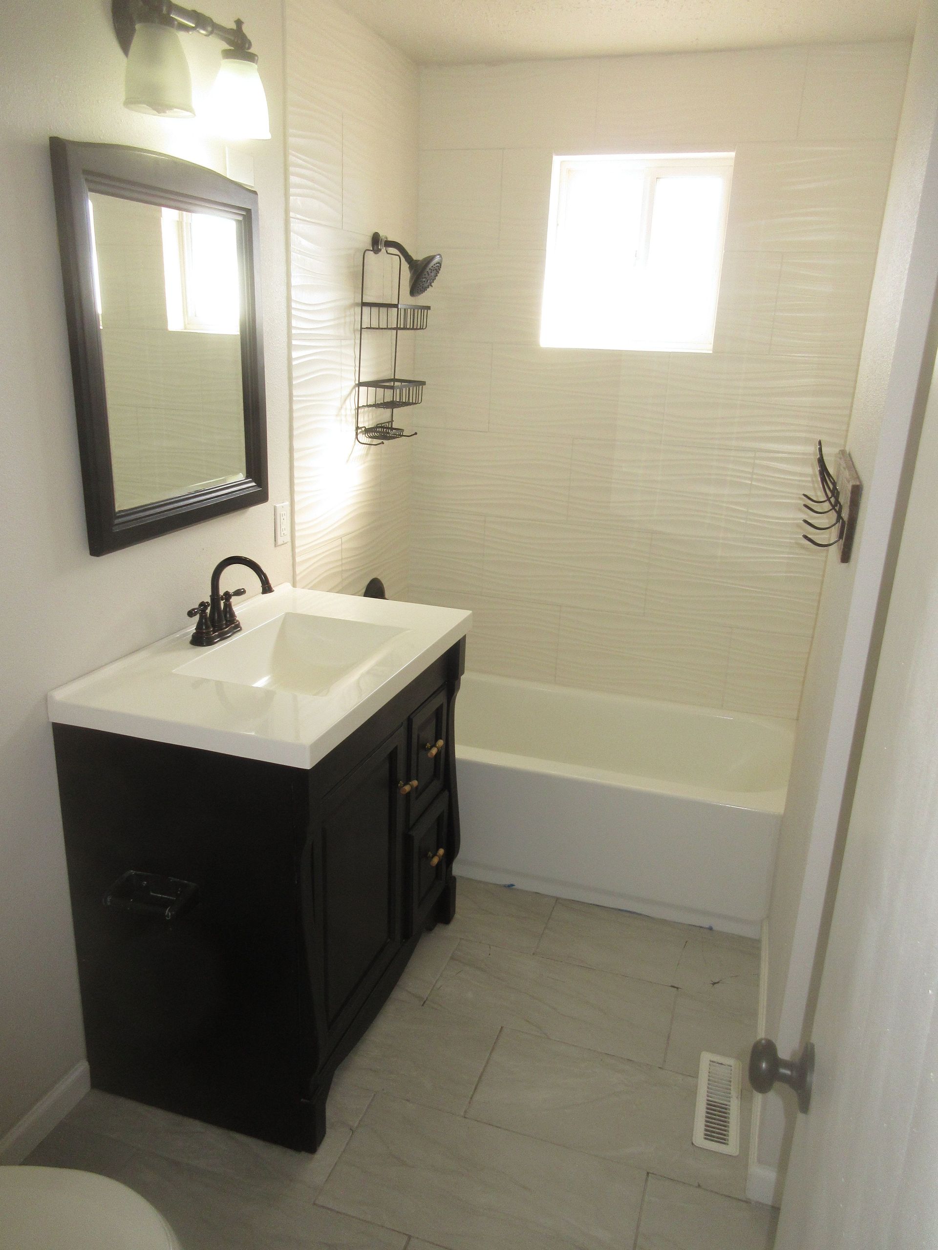 A bathroom with a sink , tub and mirror