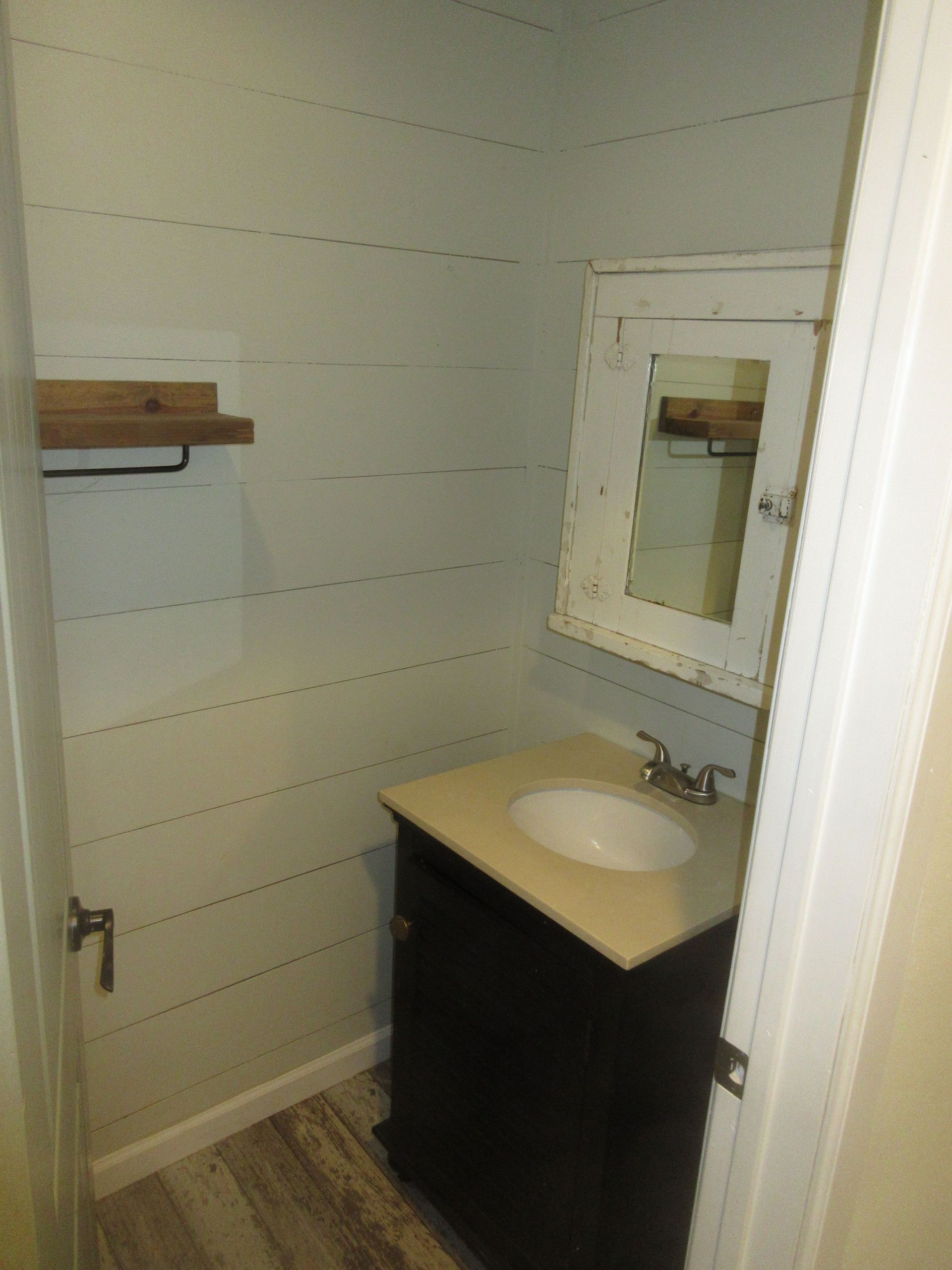 A bathroom with a sink , mirror and shelf.