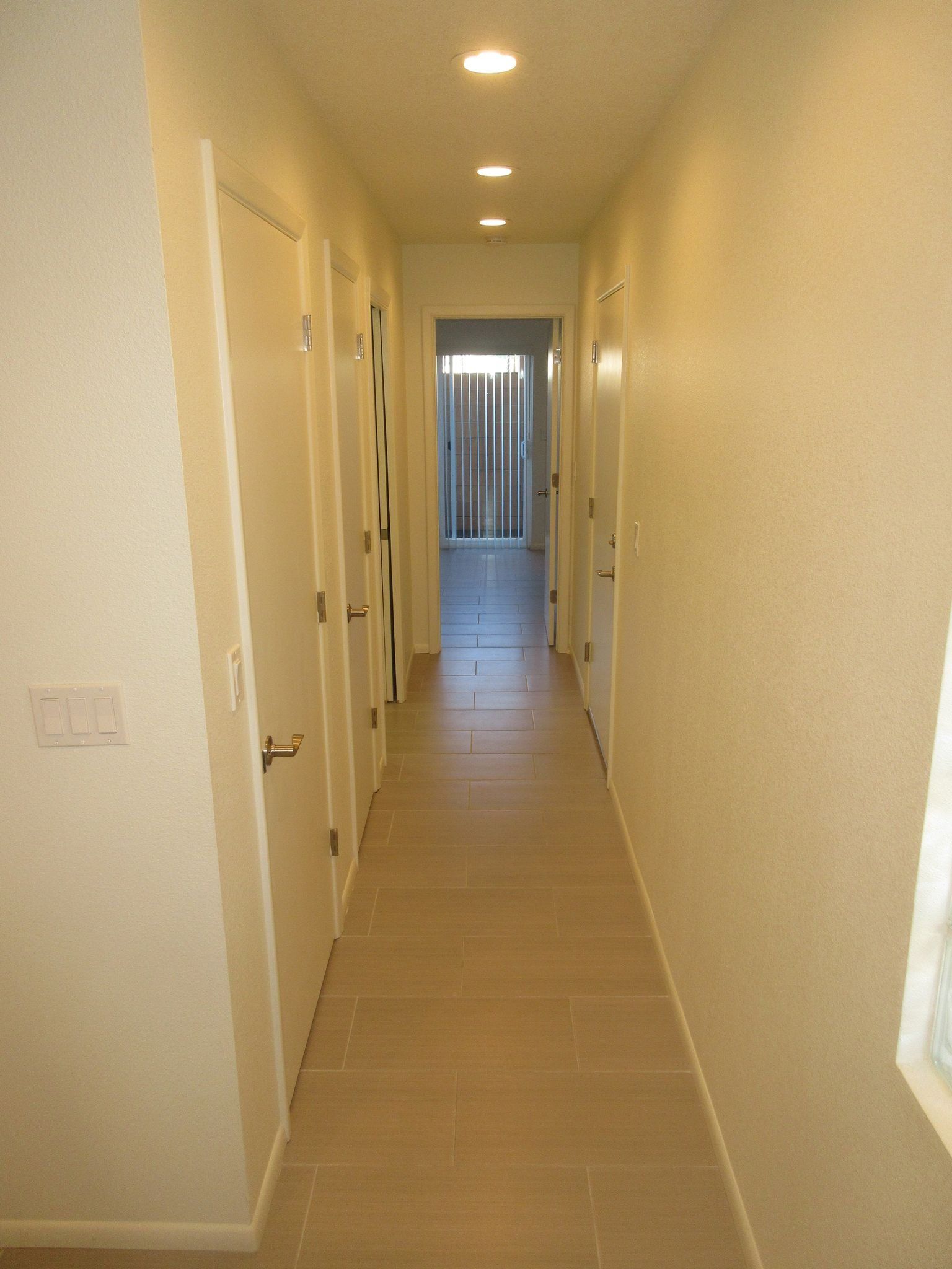 A long hallway with white walls and tile floors