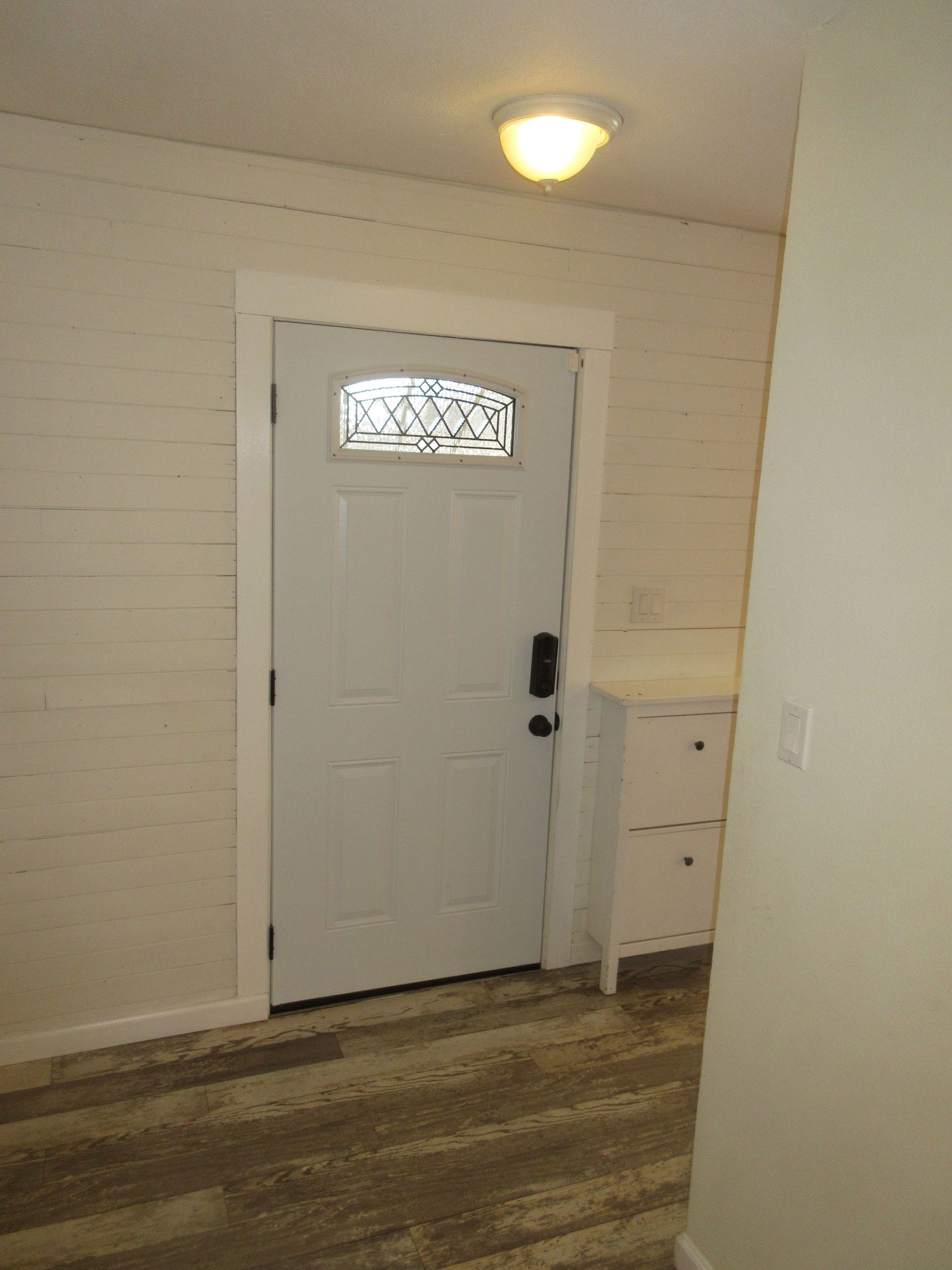 A white door with a window in a hallway.