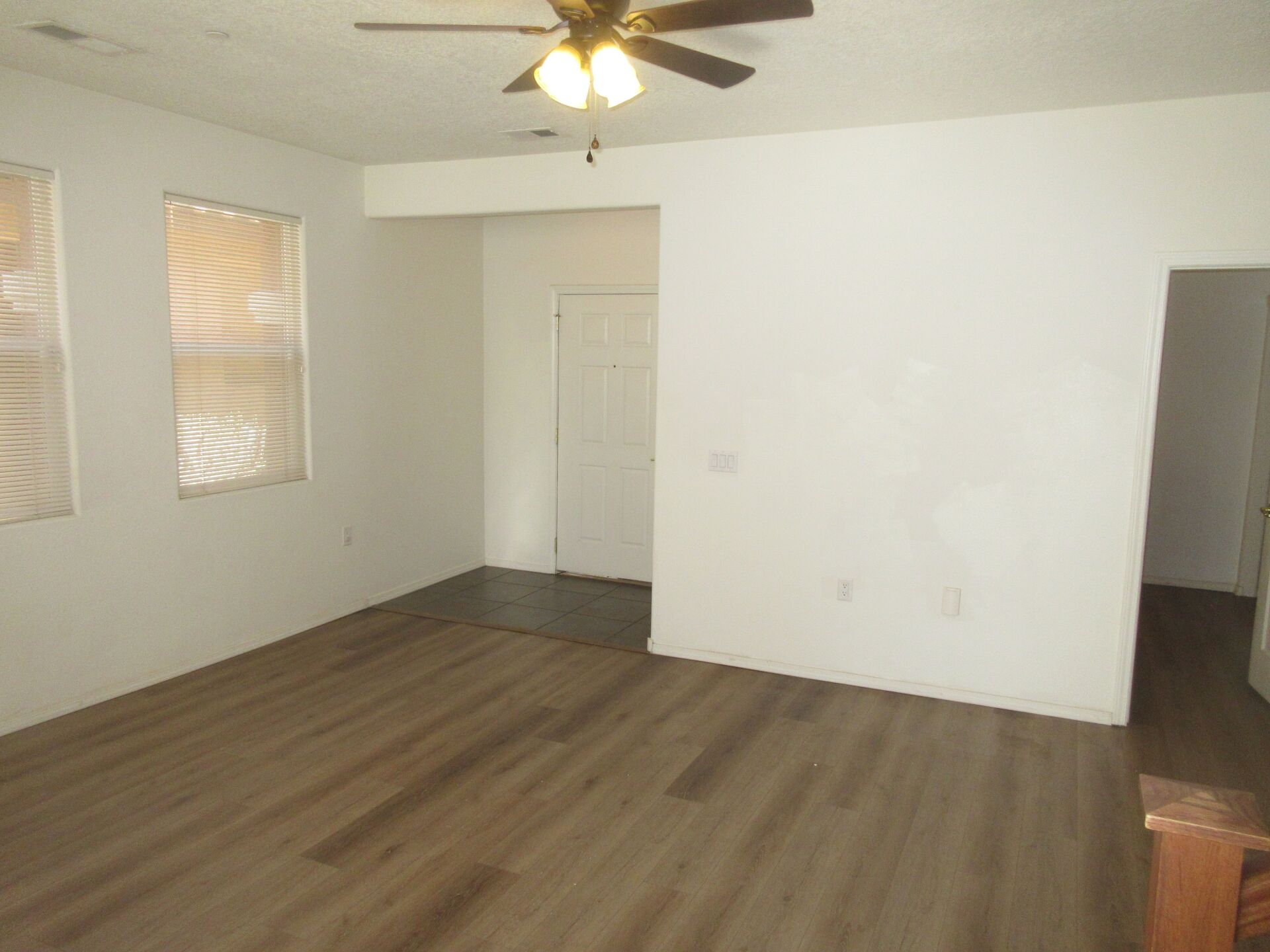 An empty living room with hardwood floors and a ceiling fan.
