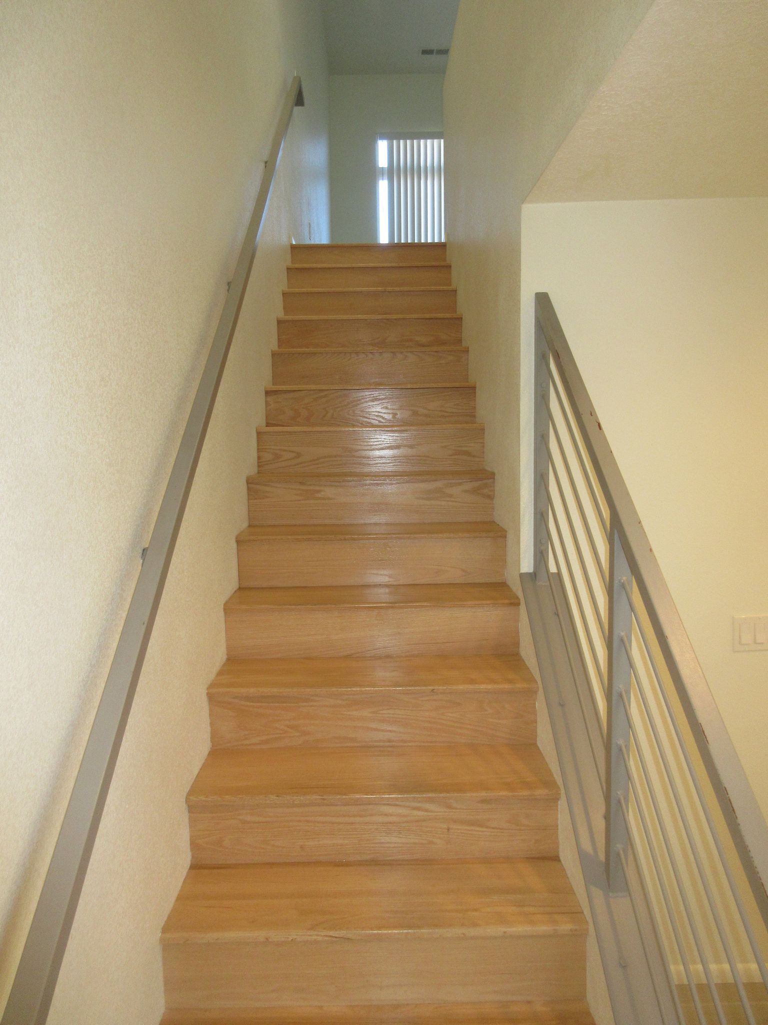 A set of wooden stairs with a metal railing