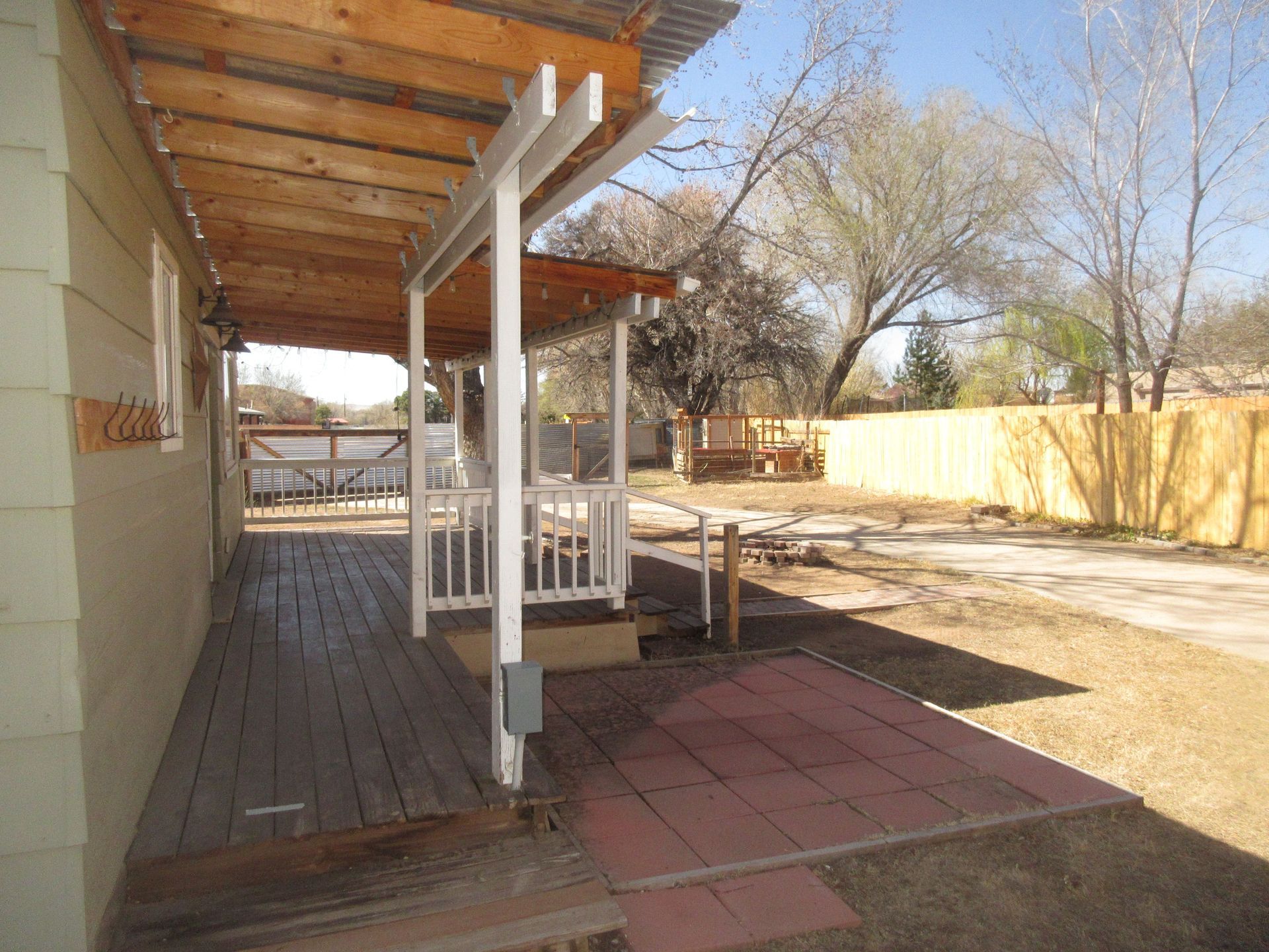 There is a porch with a wooden roof and a white railing.