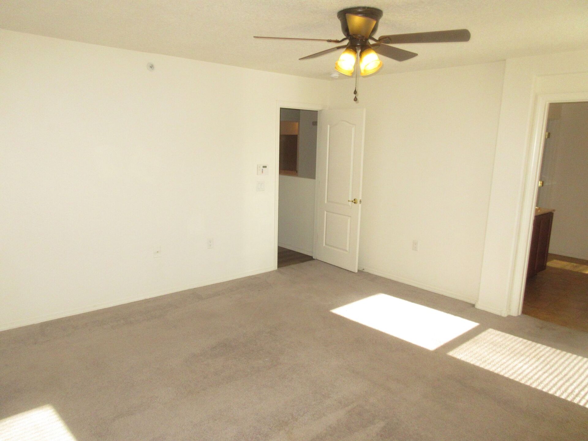 An empty room with a ceiling fan and a window