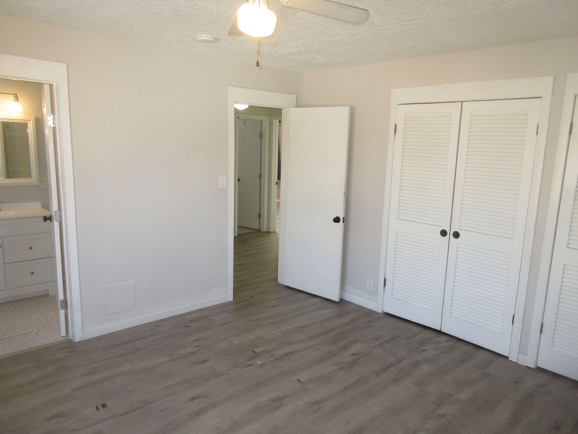An empty bedroom with a ceiling fan and closets