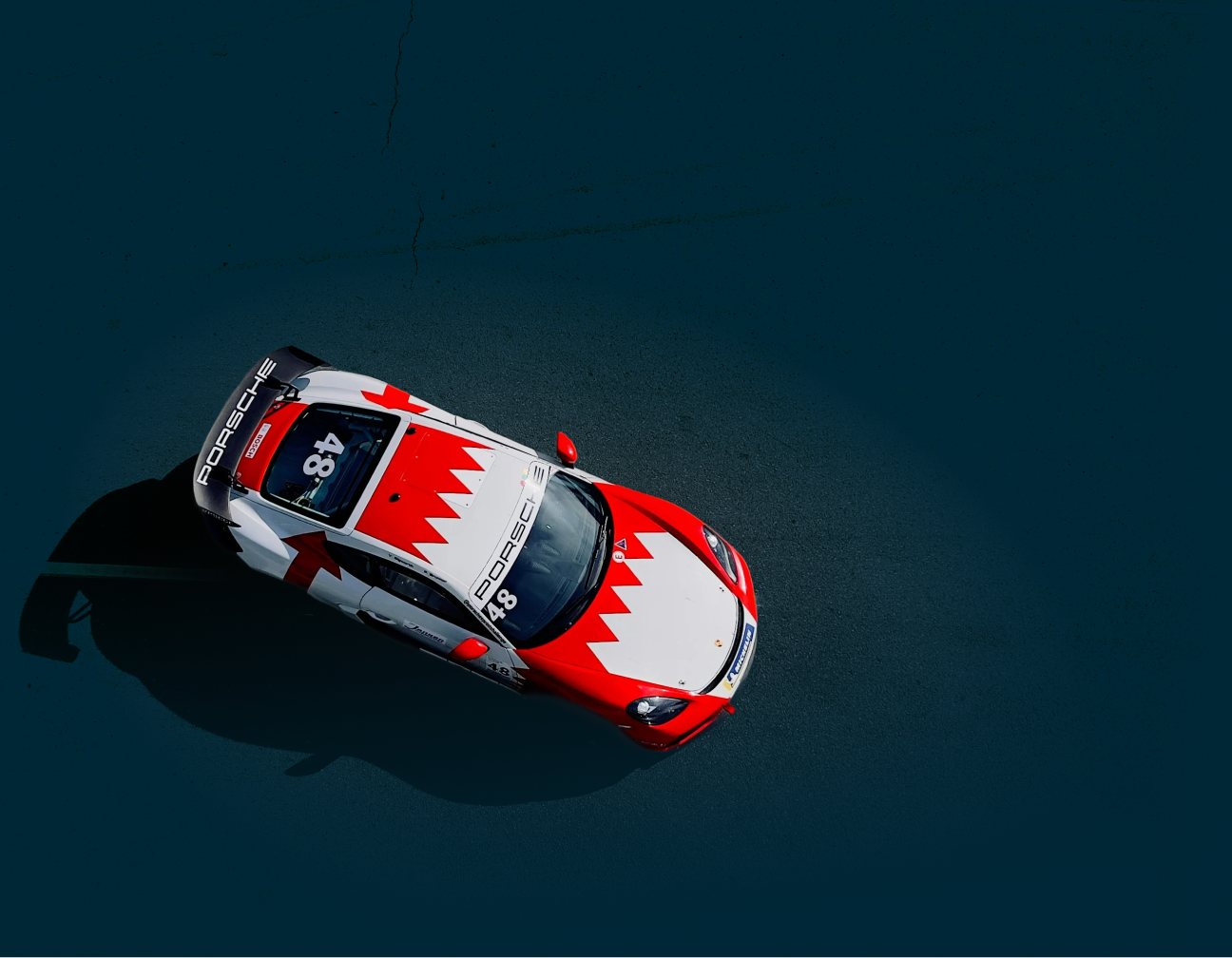 Bahraini race car, red and white, on dark track. Number 48 on top.