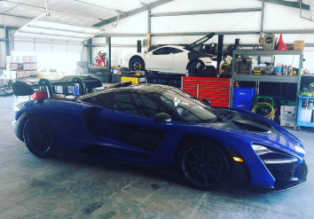 Blue McLaren Senna in a car repair shop; another car on a lift.