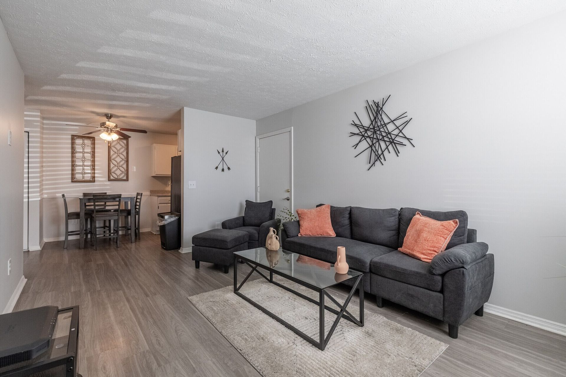Living room with gray sofa, orange pillows, coffee table, and dining area at Glastonbury Woods Apartments