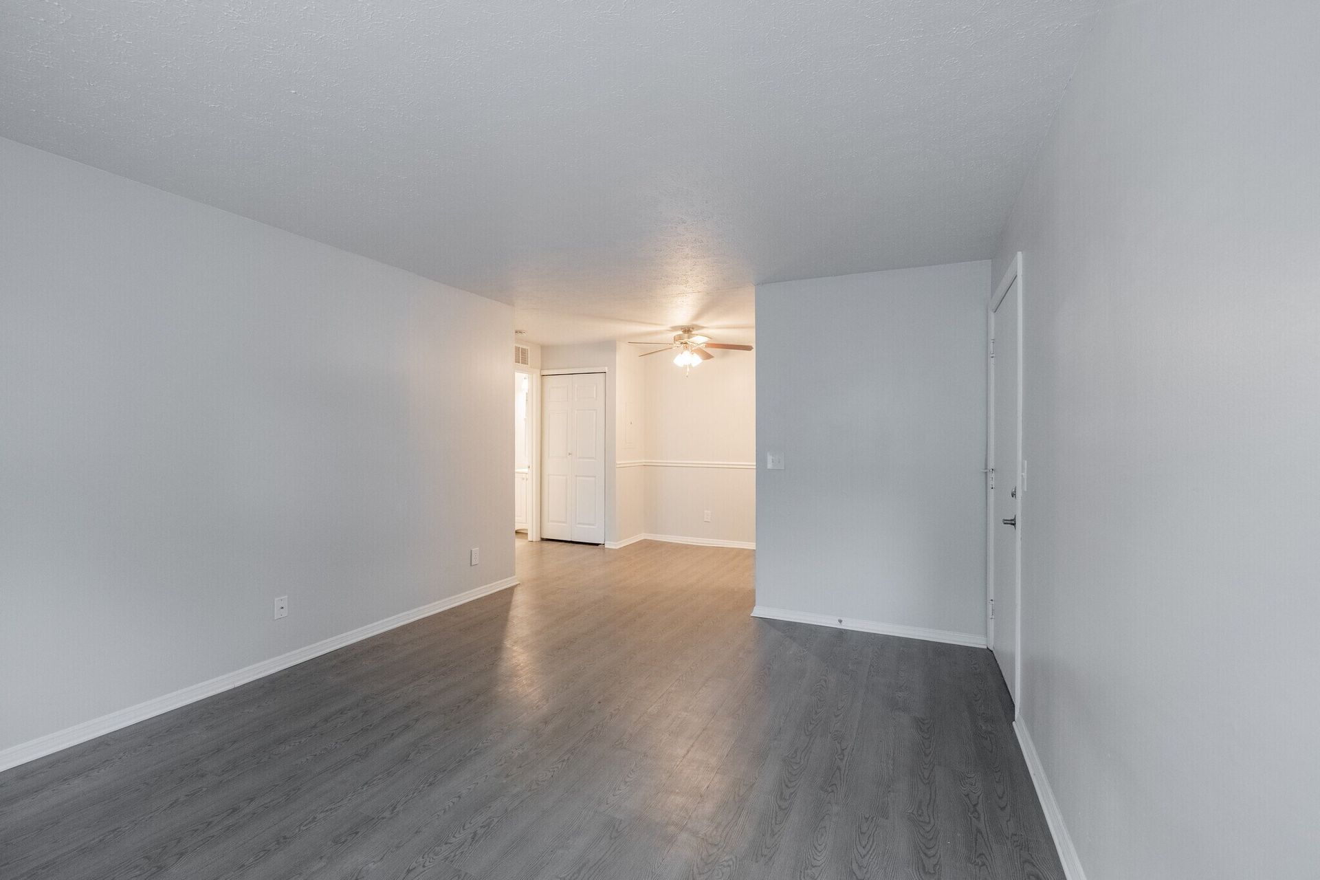 Empty apartment interior with grey flooring, white walls, and an open doorway at  Glastonbury Woods Apartments.