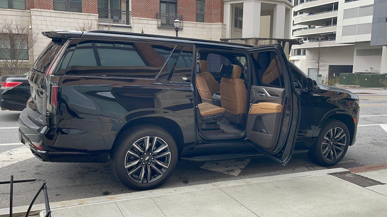 Black Cadillac Escalade waiting curbside with rear passenger door open for luxury car service in Atlanta
