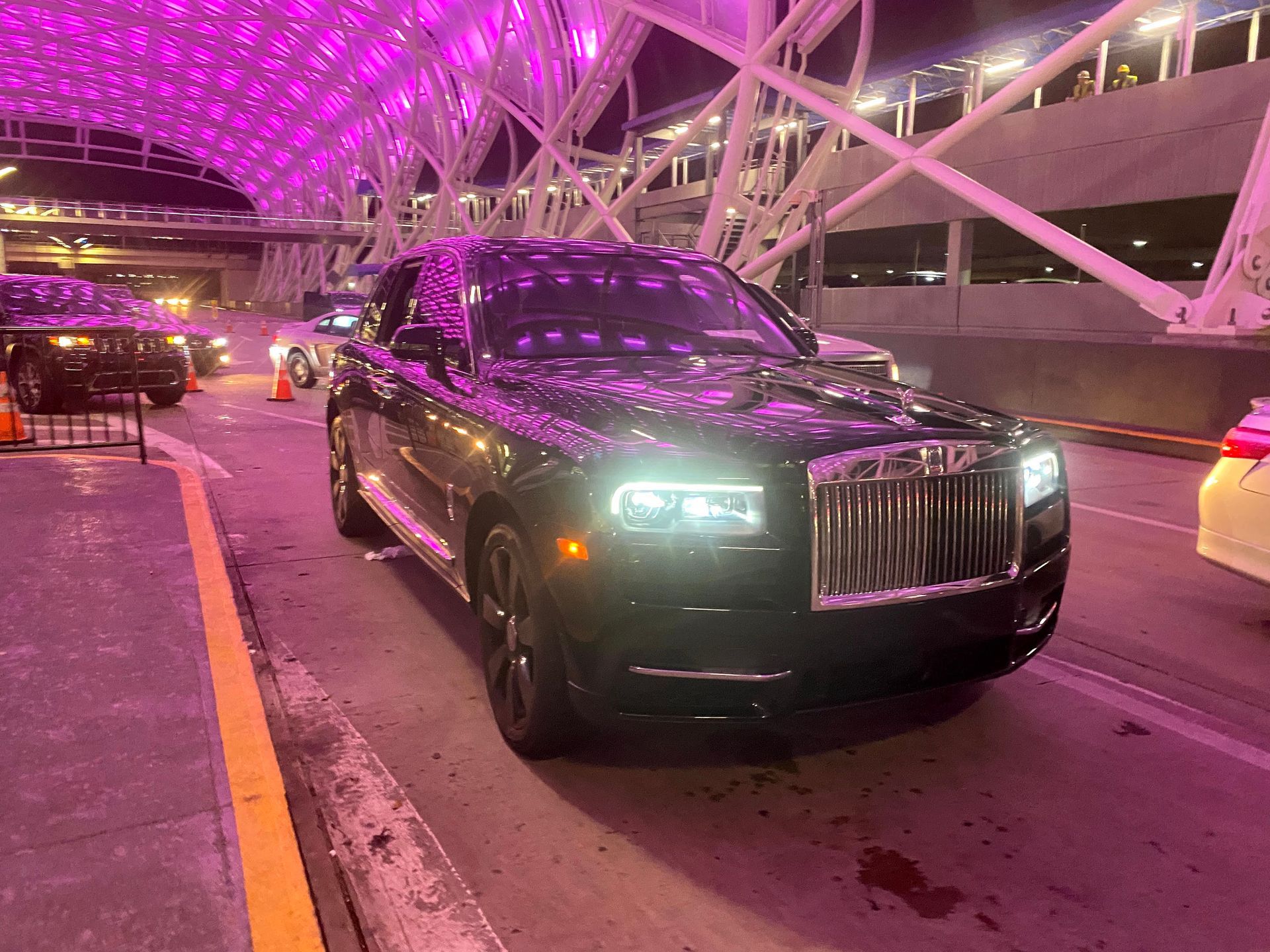 Black Rolls Royce Cullinan waiting at Atlanta airport at night for luxury car service
