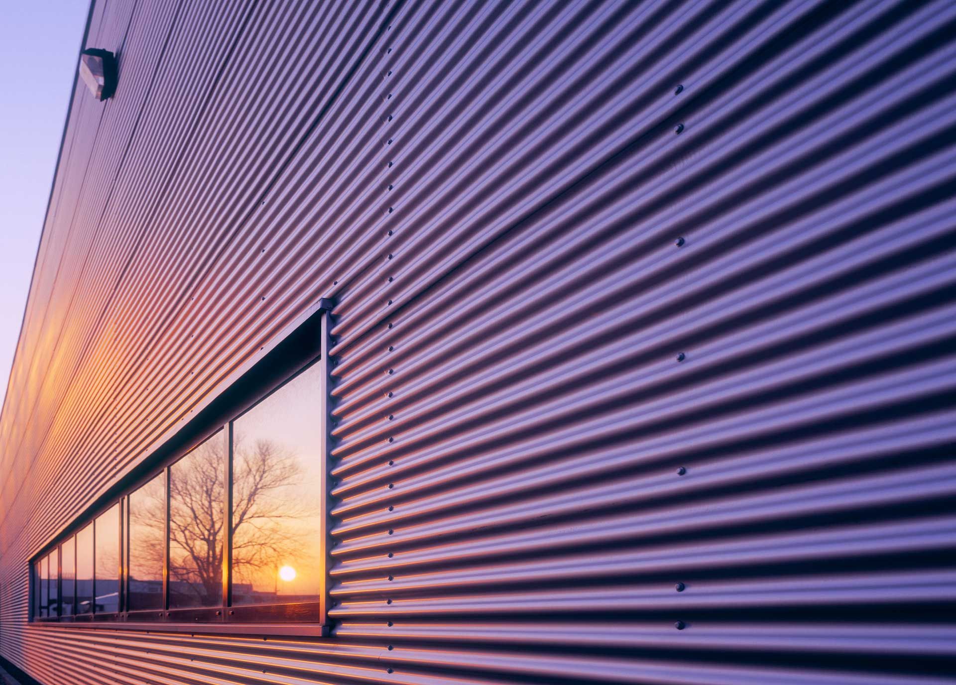 Building exterior with corrugated metal siding reflecting a sunset.