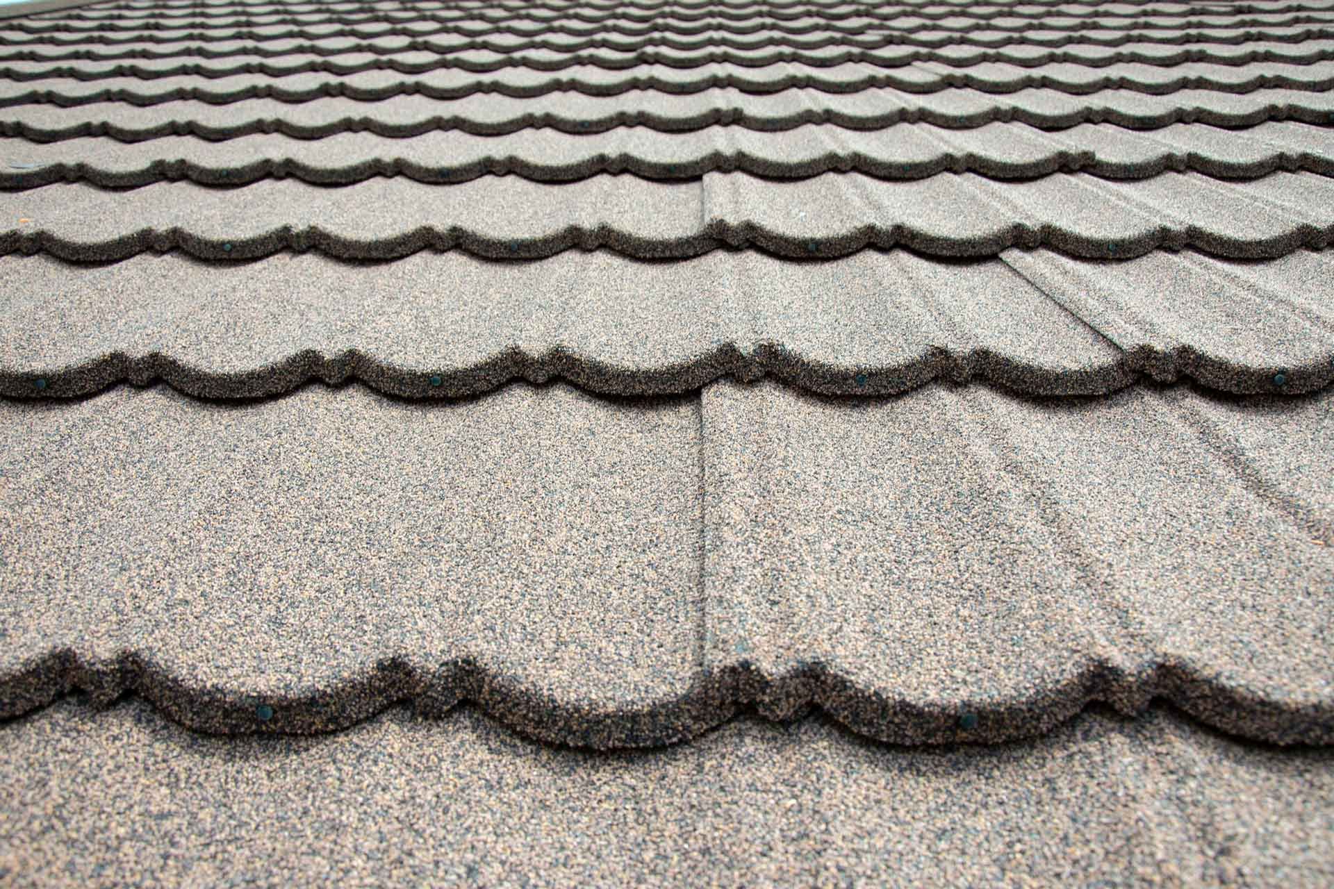 Close-up of a gray stone-coated metal roof with wavy edge detail.