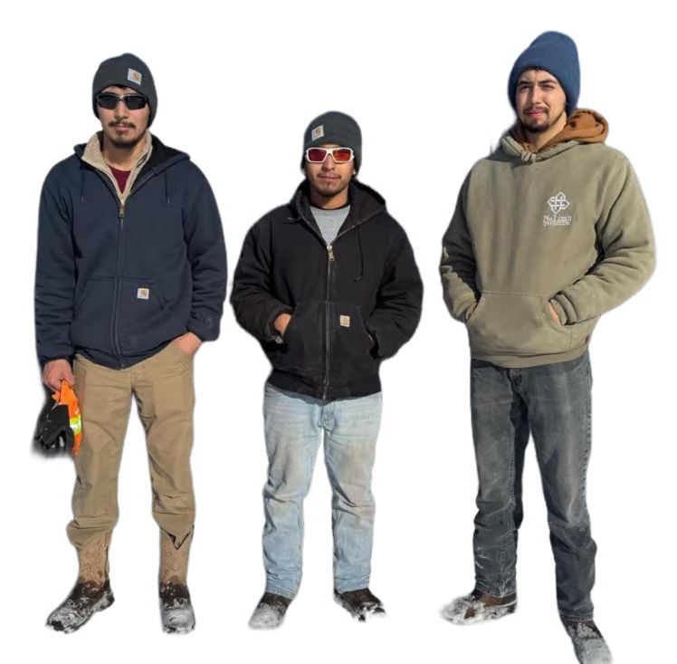 Three men in winter workwear, wearing hats, jackets, and work boots, standing outside. Three men in winter workwear, wearing hats, jackets, and work boots, standing outside.