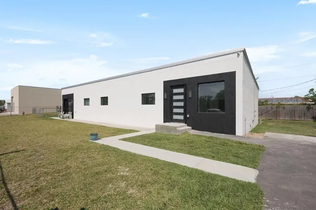 a newly painted house with a black door is sitting on top of a lush green field