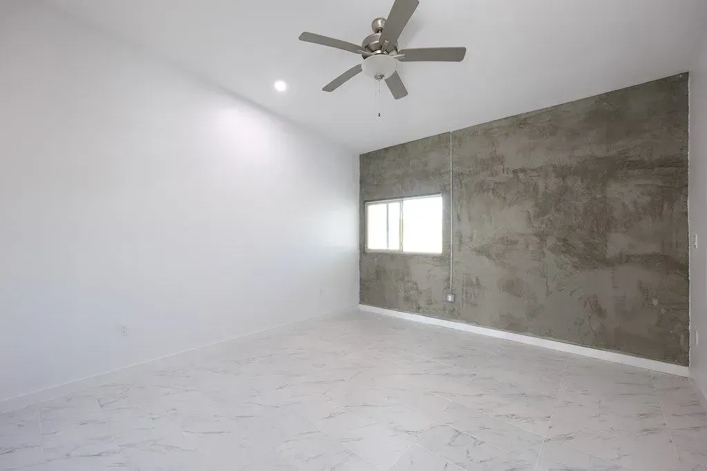an empty room with a ceiling fan and a window
