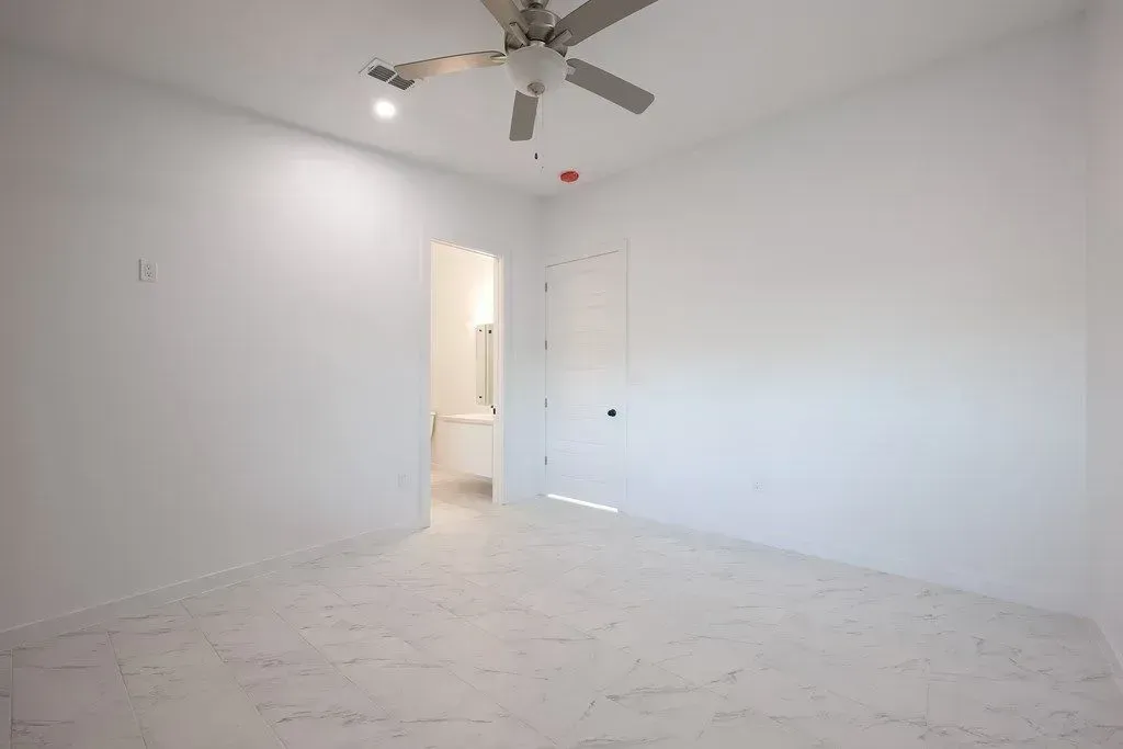 a newly painted bedroom with a ceiling fan and a door leading to a bathroom