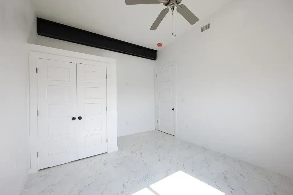 a newly painted room with white walls and a ceiling fan