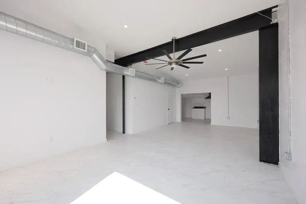 a newly painted room with white walls and a ceiling fan