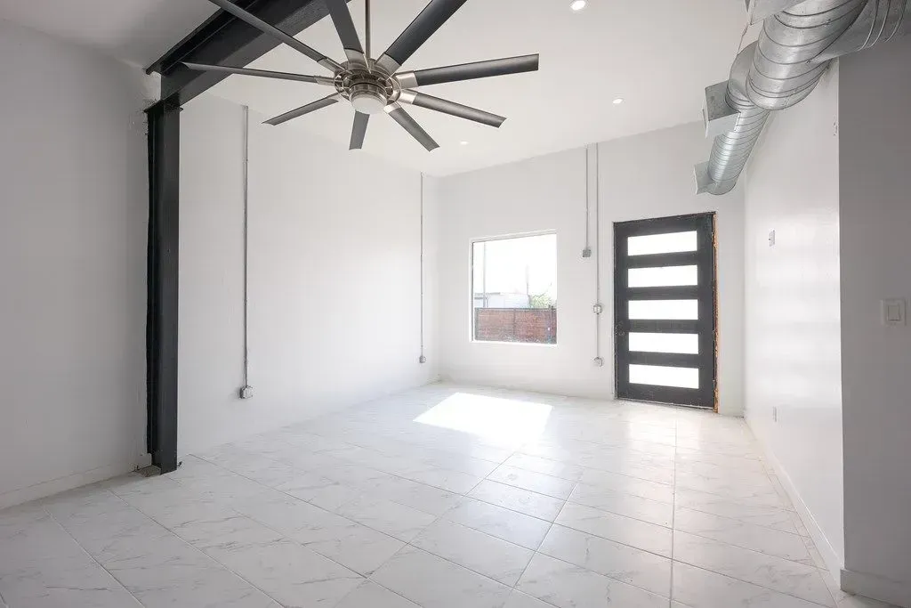 a newly painted room with a ceiling fan and a door